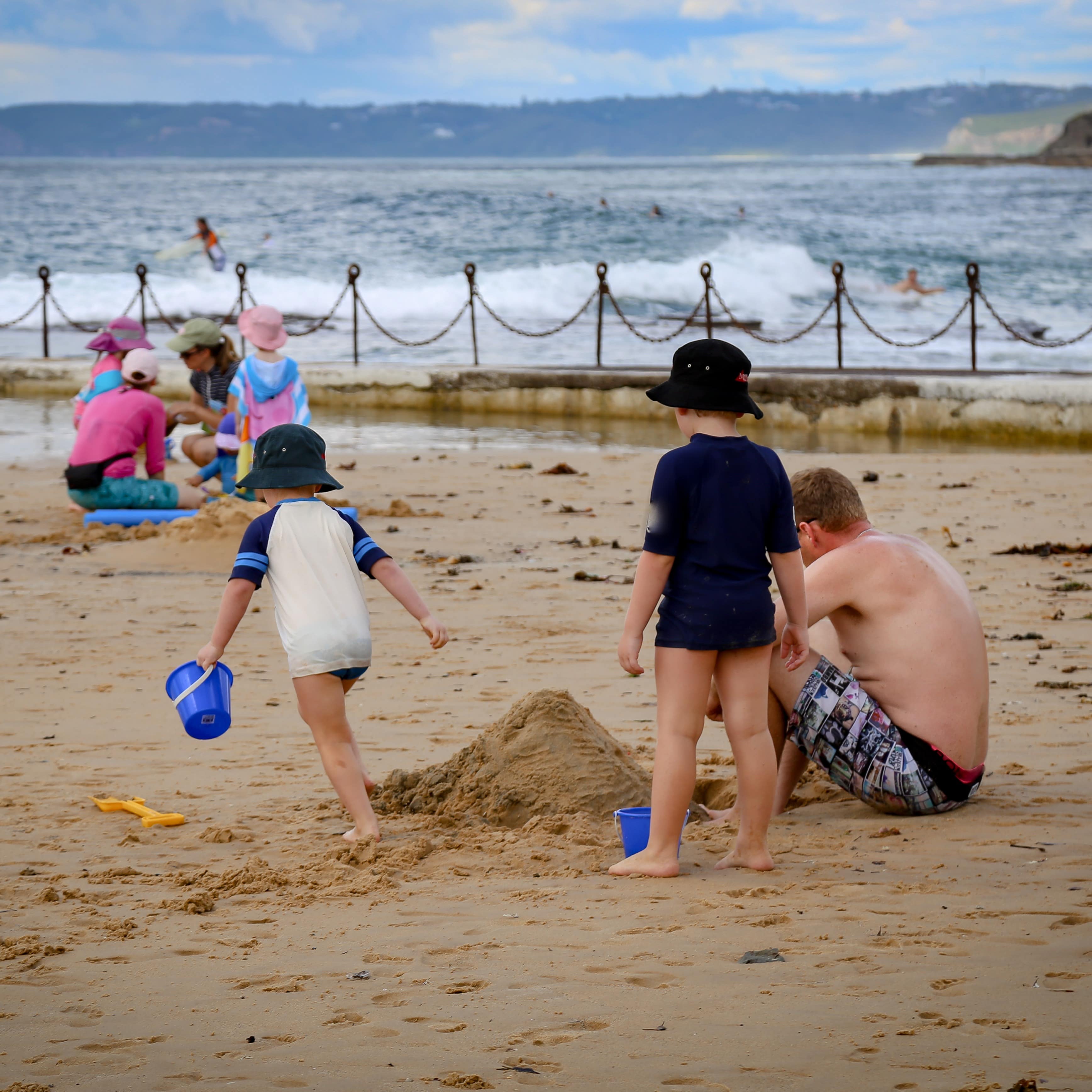 Father and sons building sandcastles on the beach in Newcastle