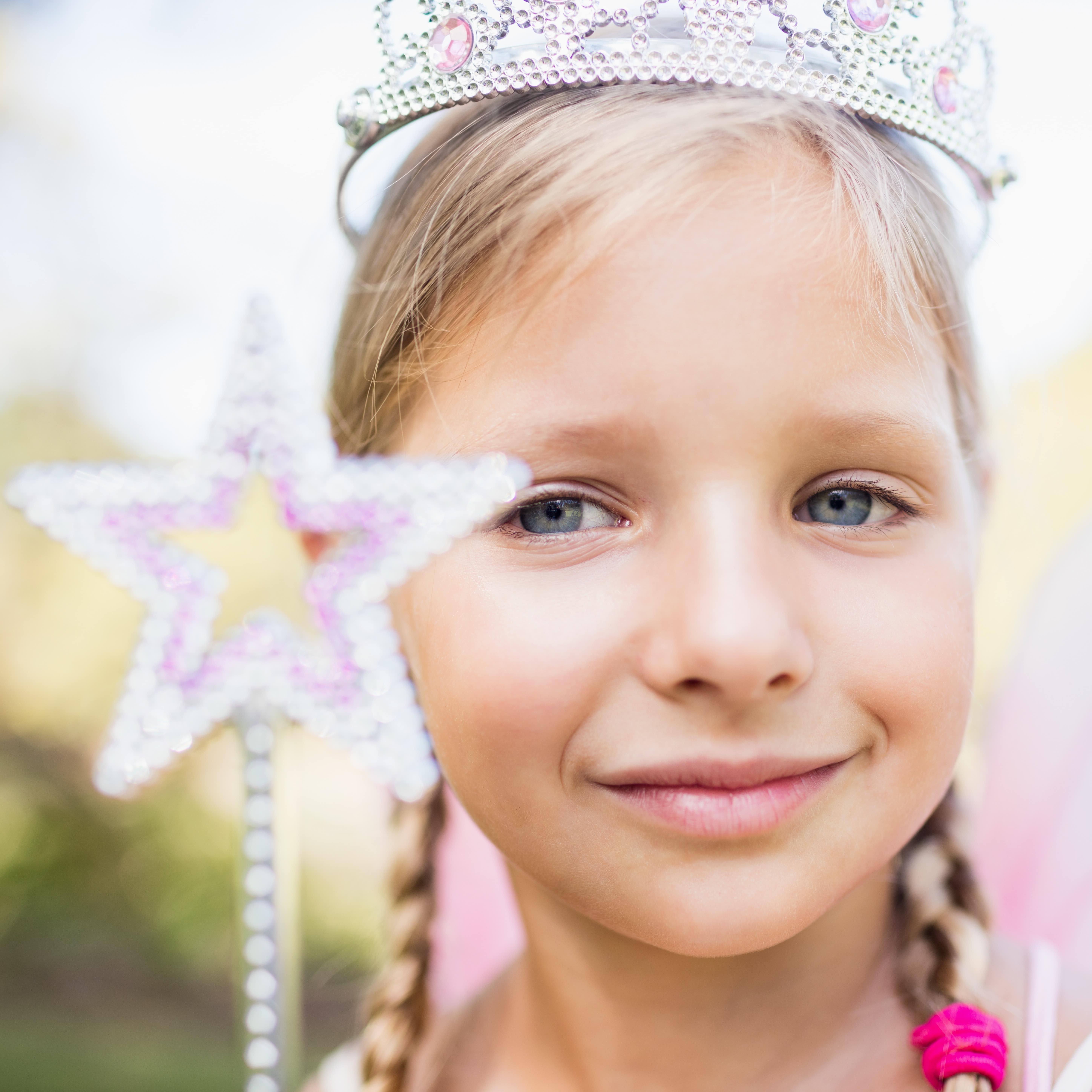 Close-up portrait of adorable girl dressed as a princess holding a star wand