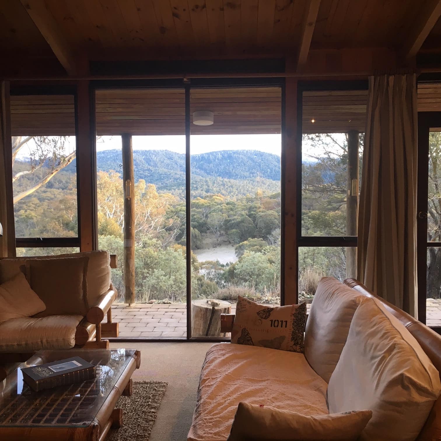 Interior of rustic log cabin overlooking trees and mountains
