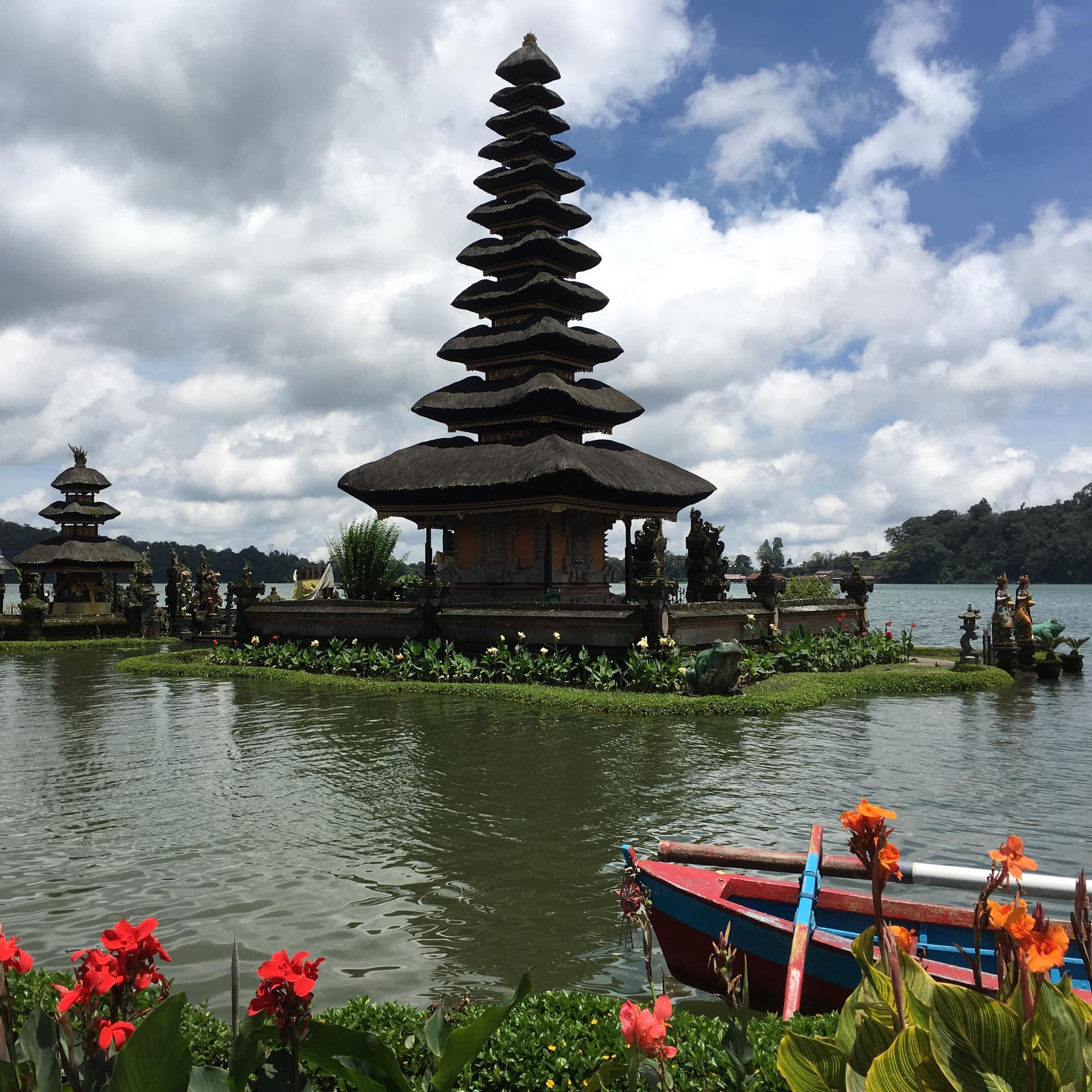 Two small pagoda temples in a lake surrounded by lush greenery.