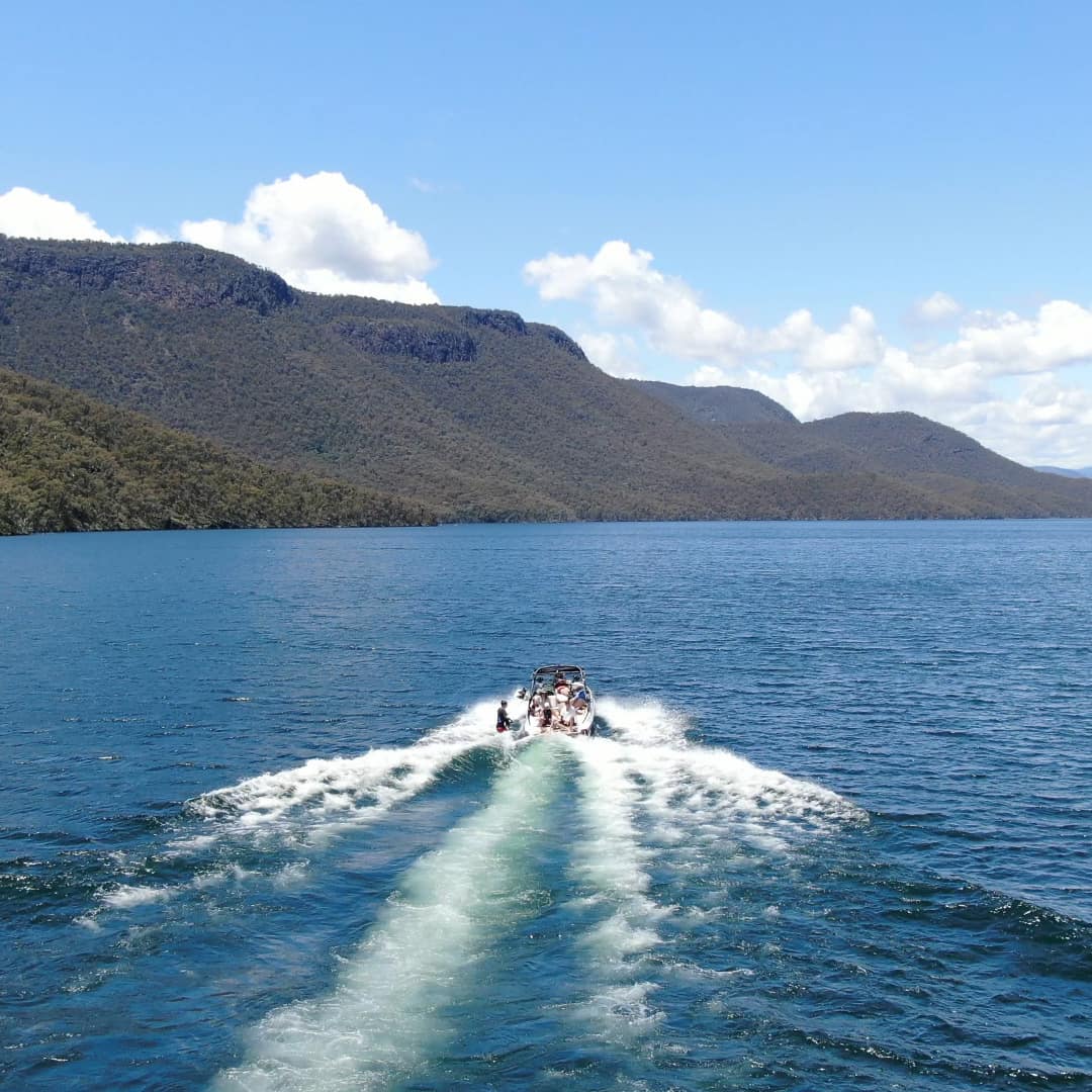 A boat riding through the water with mountains in the distance.