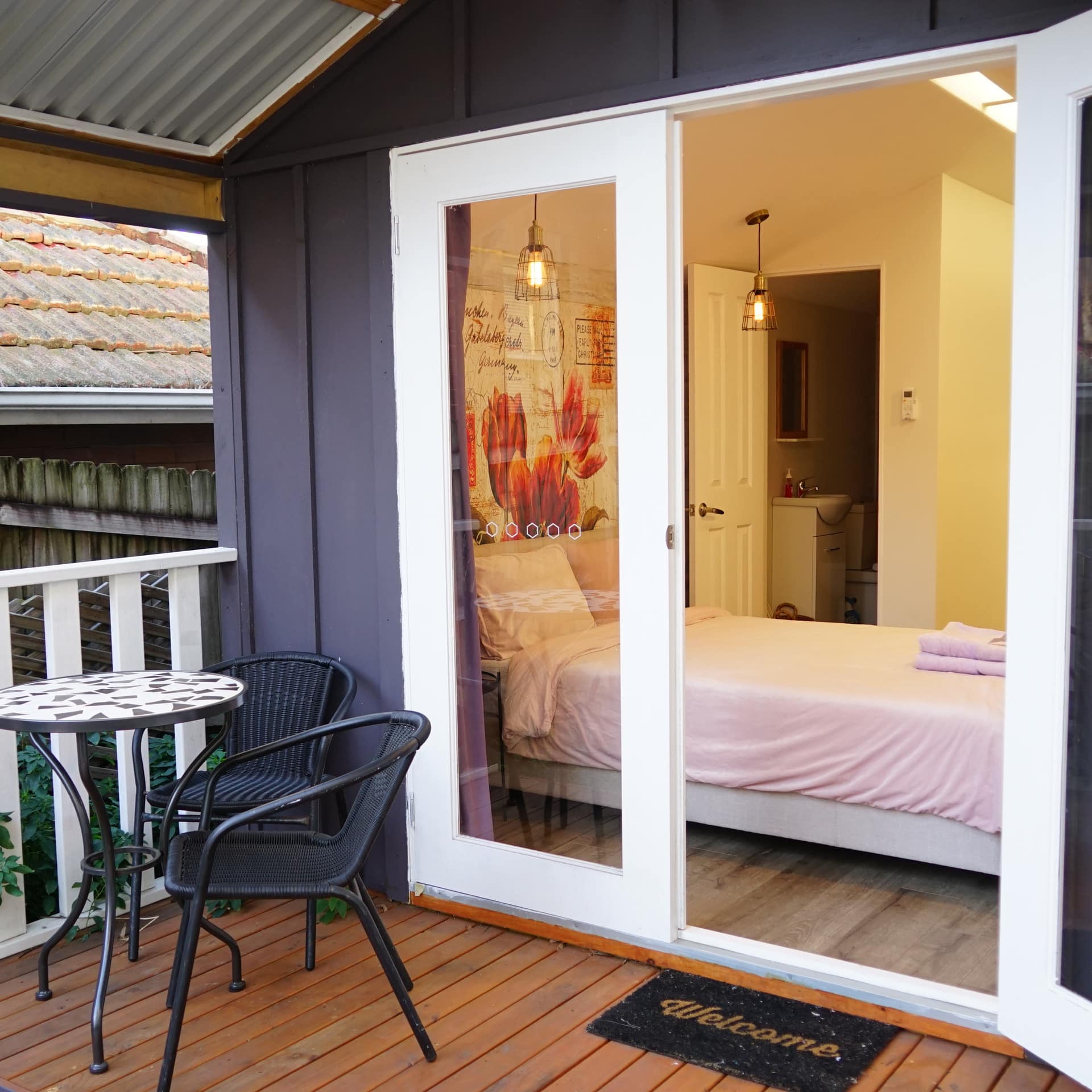 Open door view from balcony looking into a bedroom of a boutique cabin