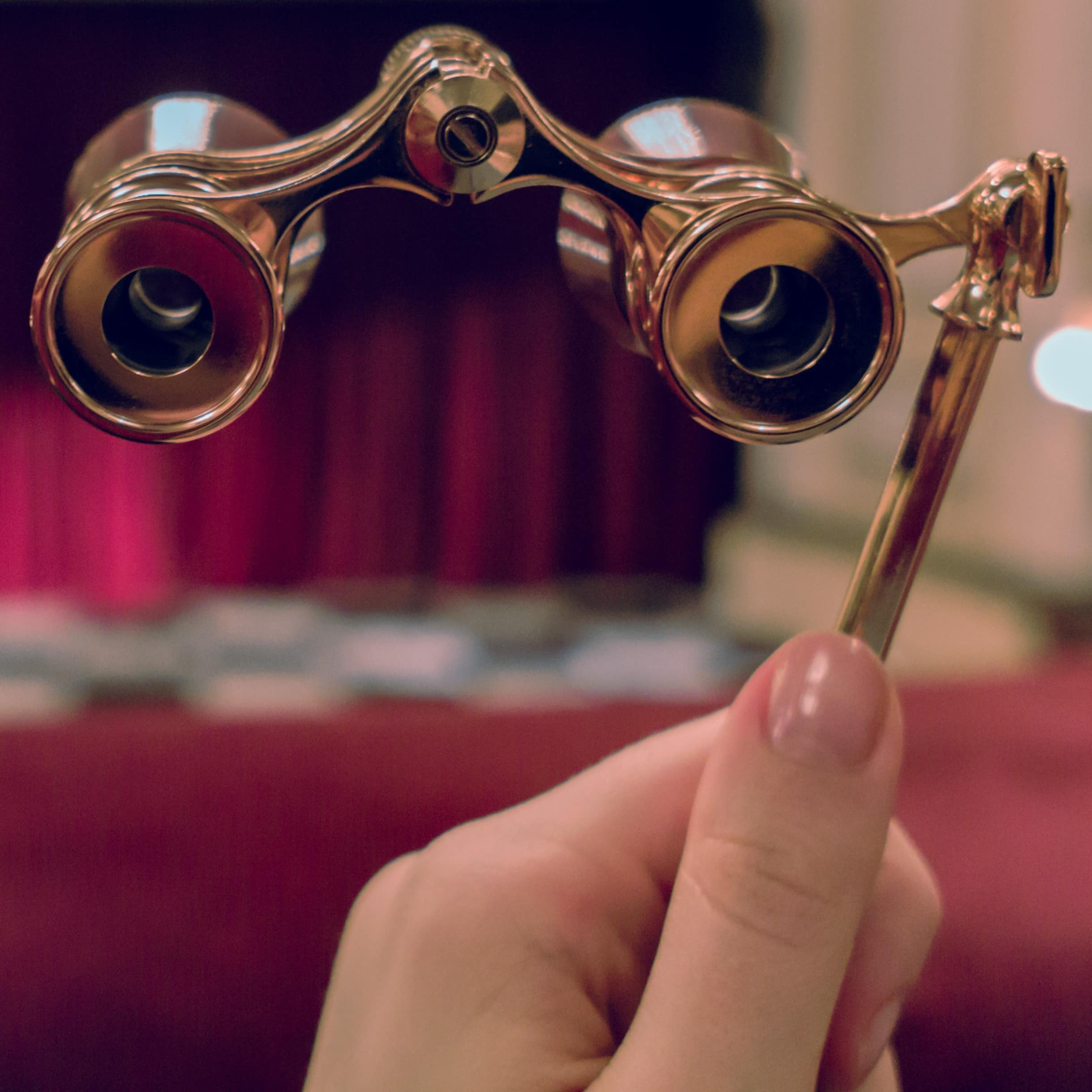 Woman holding opera glasses with stage in background