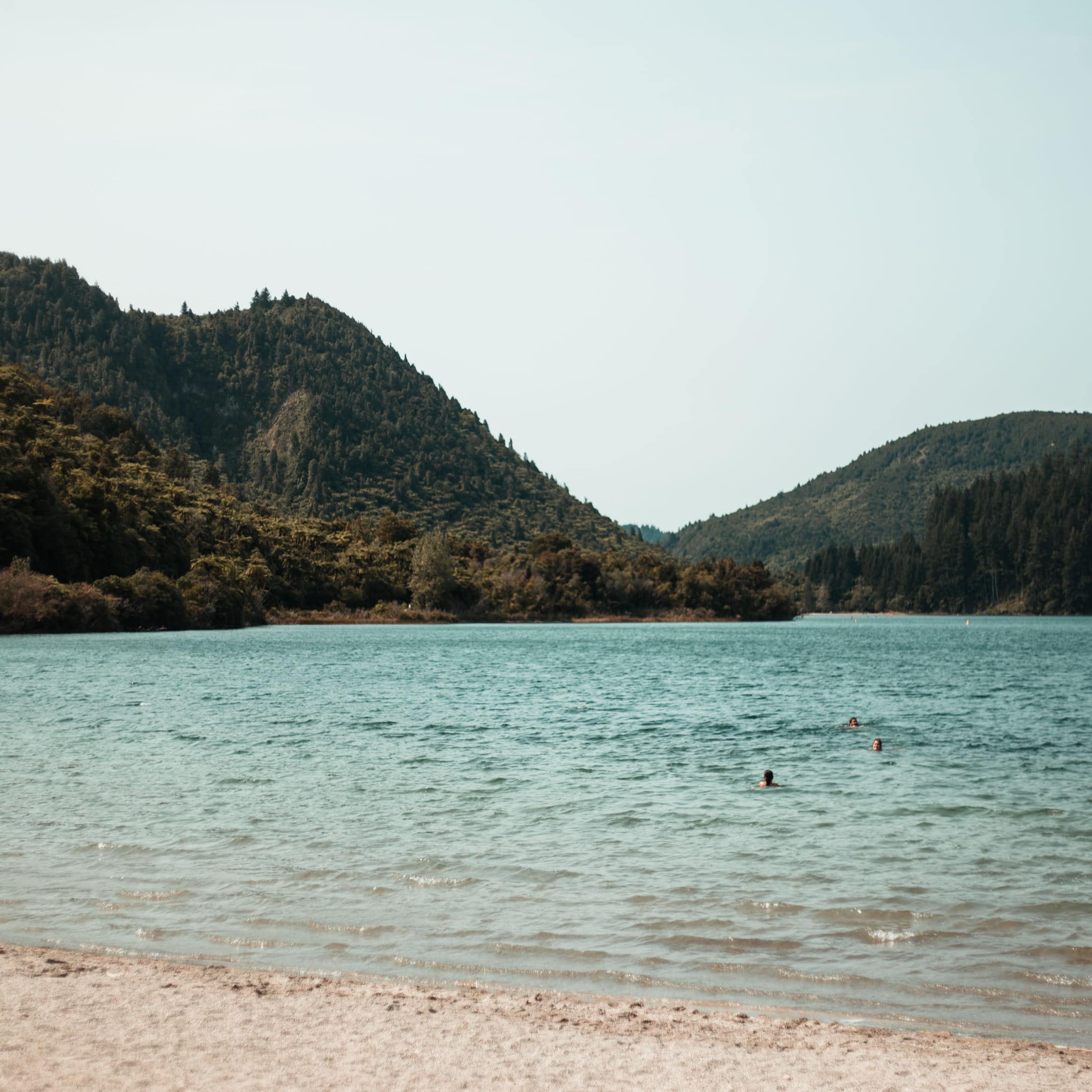 People swimming in Lake Tikitapu, surrounded by hills