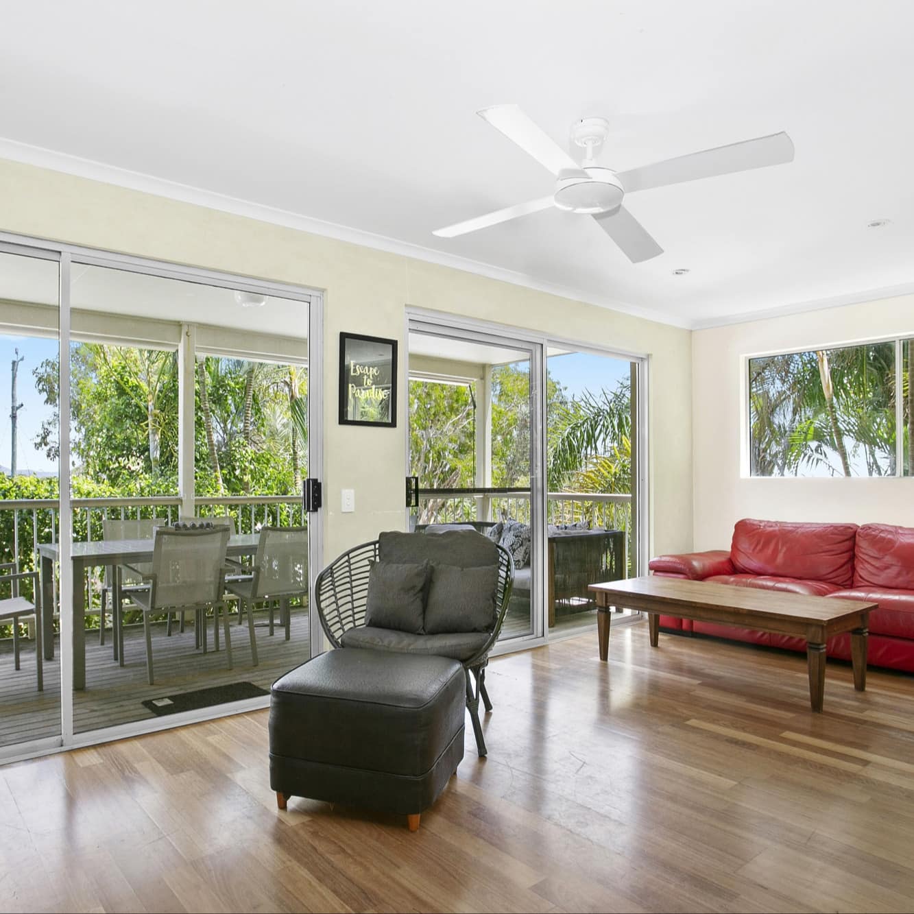 Living room of 3-bedroom beach townhouse with red leather sofa, hardwood floors and balcony with outdoor dining and sofa