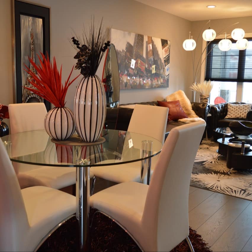 Interior of luxury apartment with a glass top dining table and white modern chairs, floral rug, and leather sofa and chairs