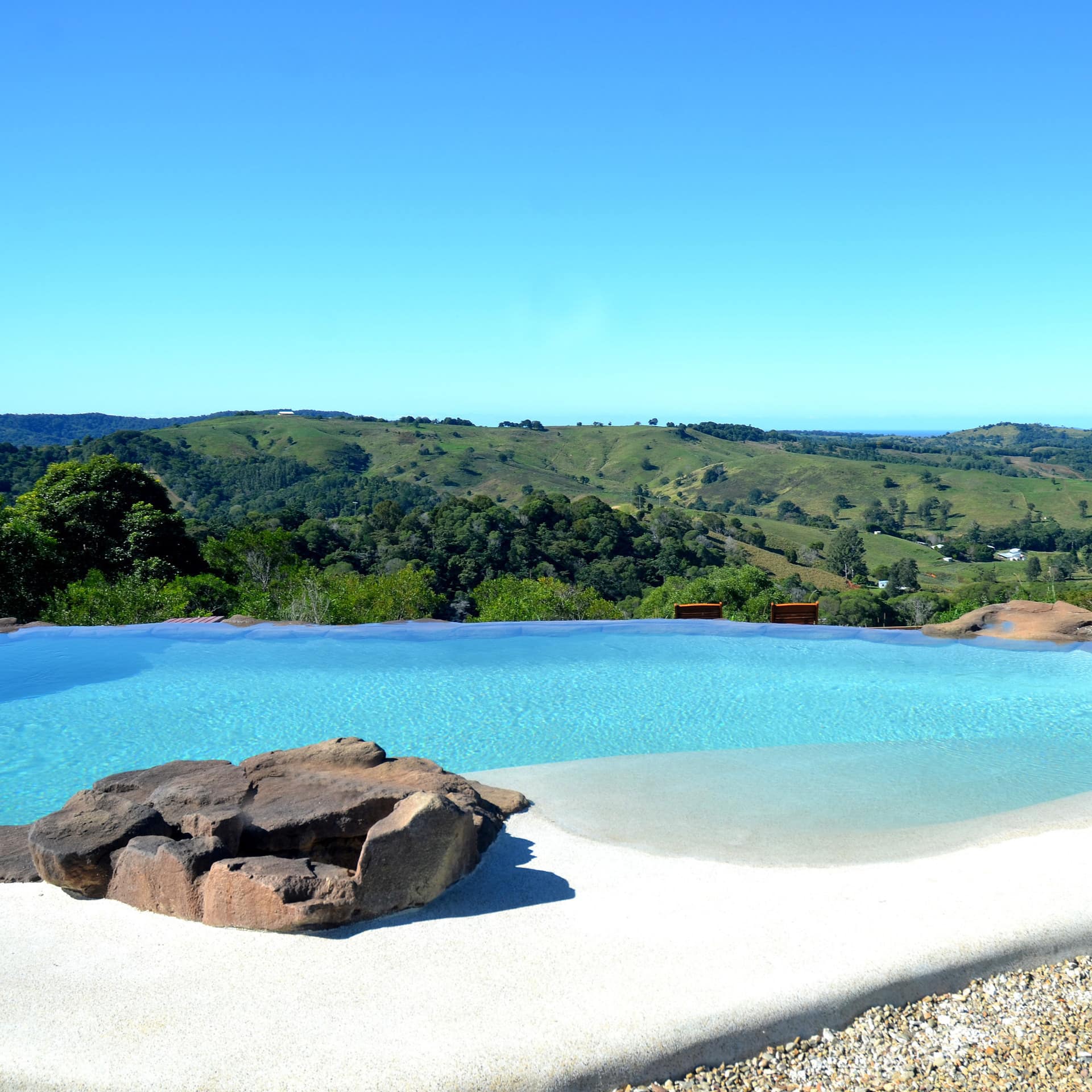 A private pool with pebble gravel pool deck, overlooking rambling hills.