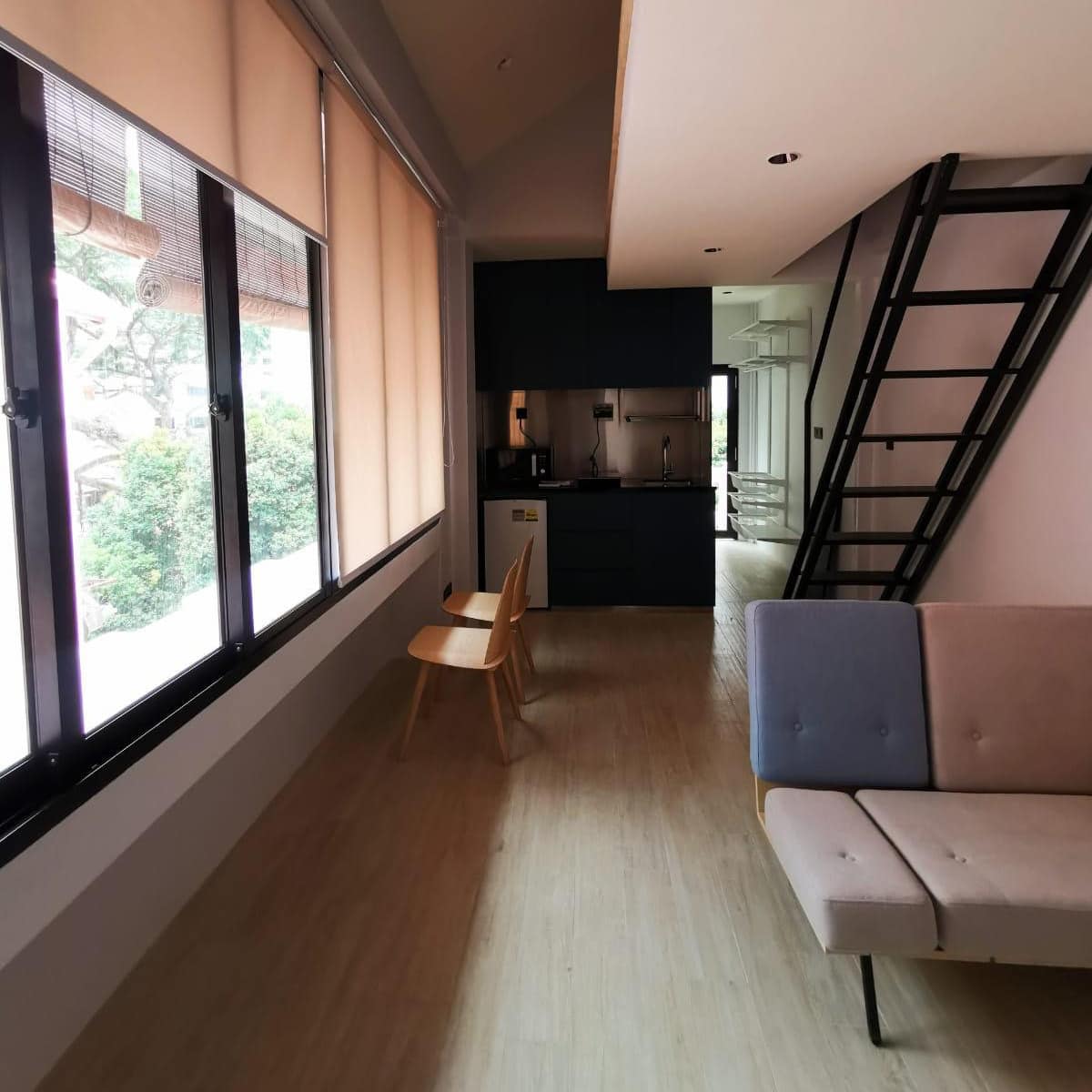 Hardwood floors in modern apartment looking into kitchen with wall of windows on the left and stairs on the right