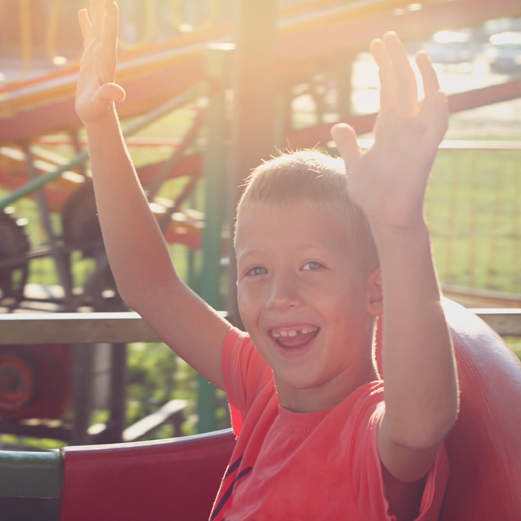 Boy smiling with hands in air on Luna Park roller coaster