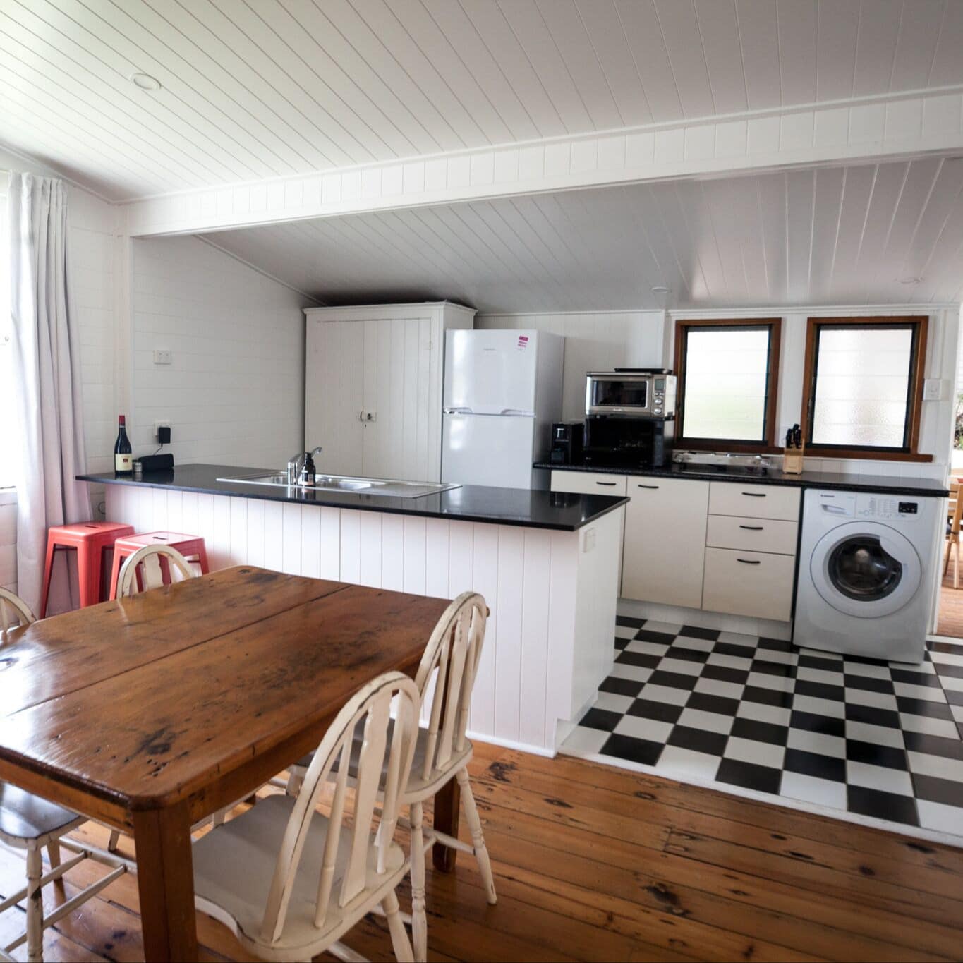 Black and white tiled kitchen and dining area with wooden table and floors with door open to patio