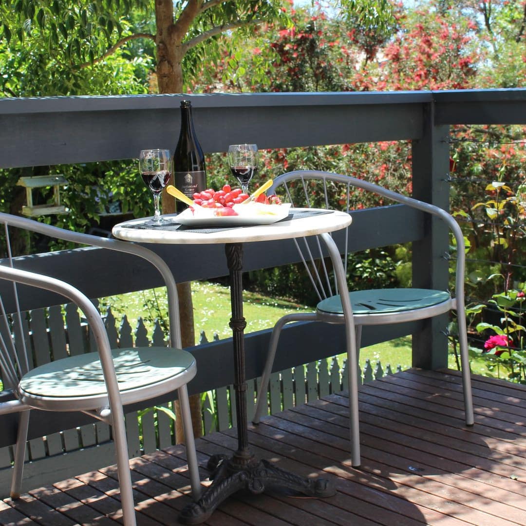 Romantic outdoor dining area on balcony of B & B surrounded by flowers and trees