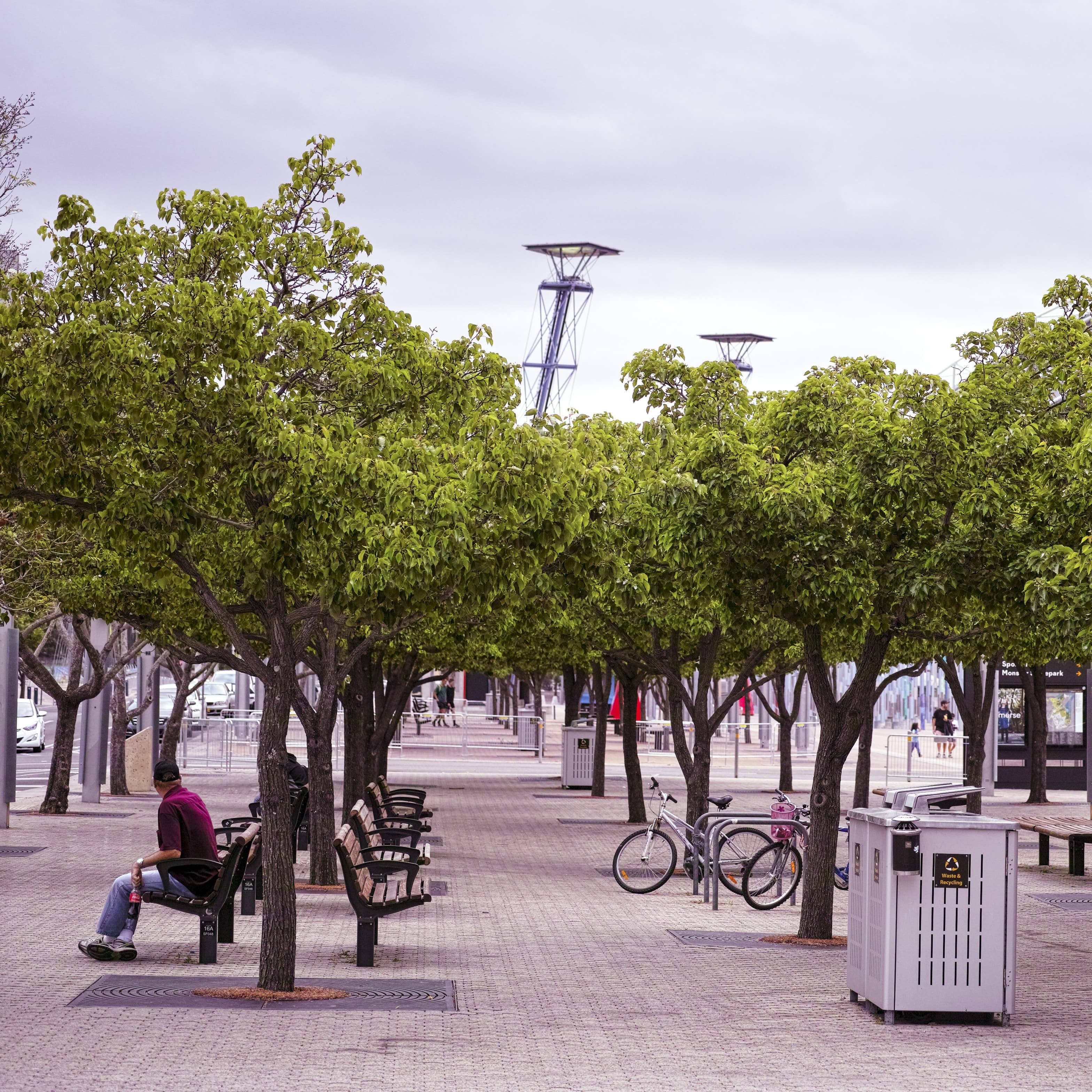 Sydney Olympic Park Railway Station public courtyard with trees and bicycle parks and people sitting on benches