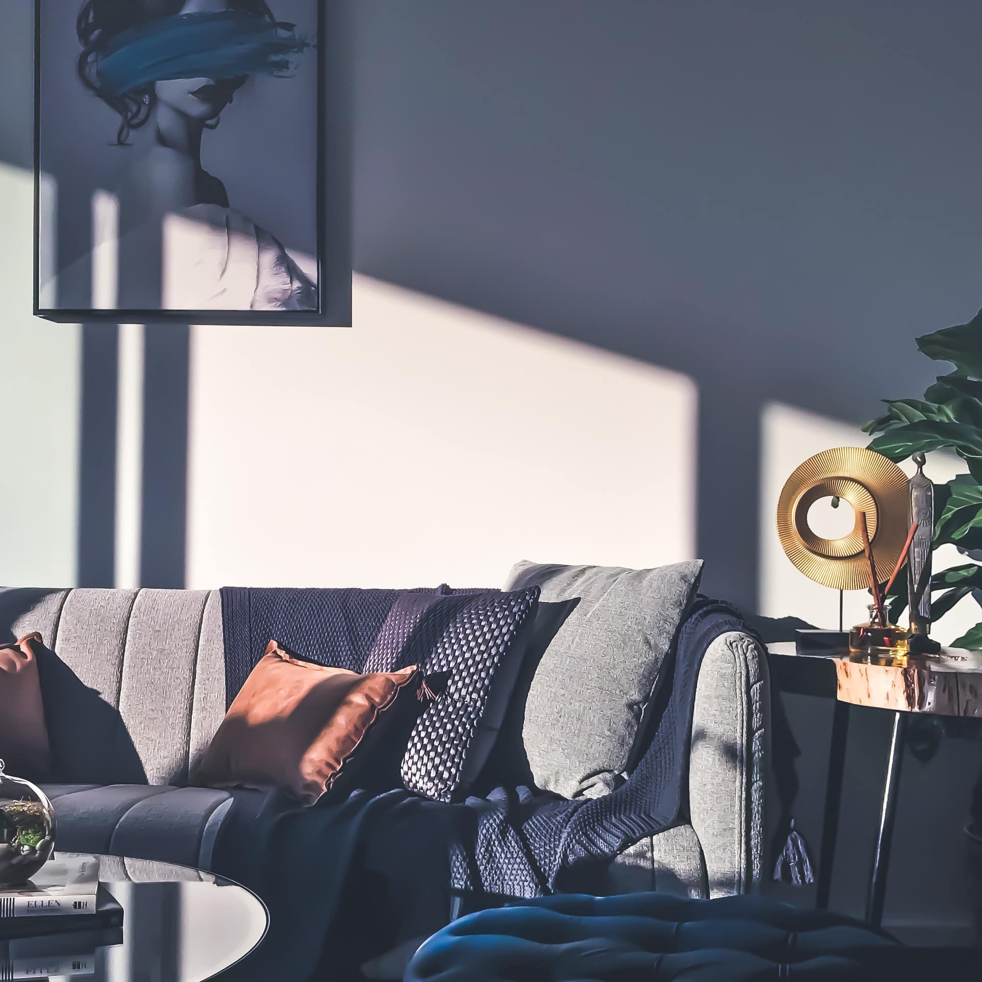 Comfortable cloth sofa with accent pillows and deep blue ottoman with soft evening light coming through the window