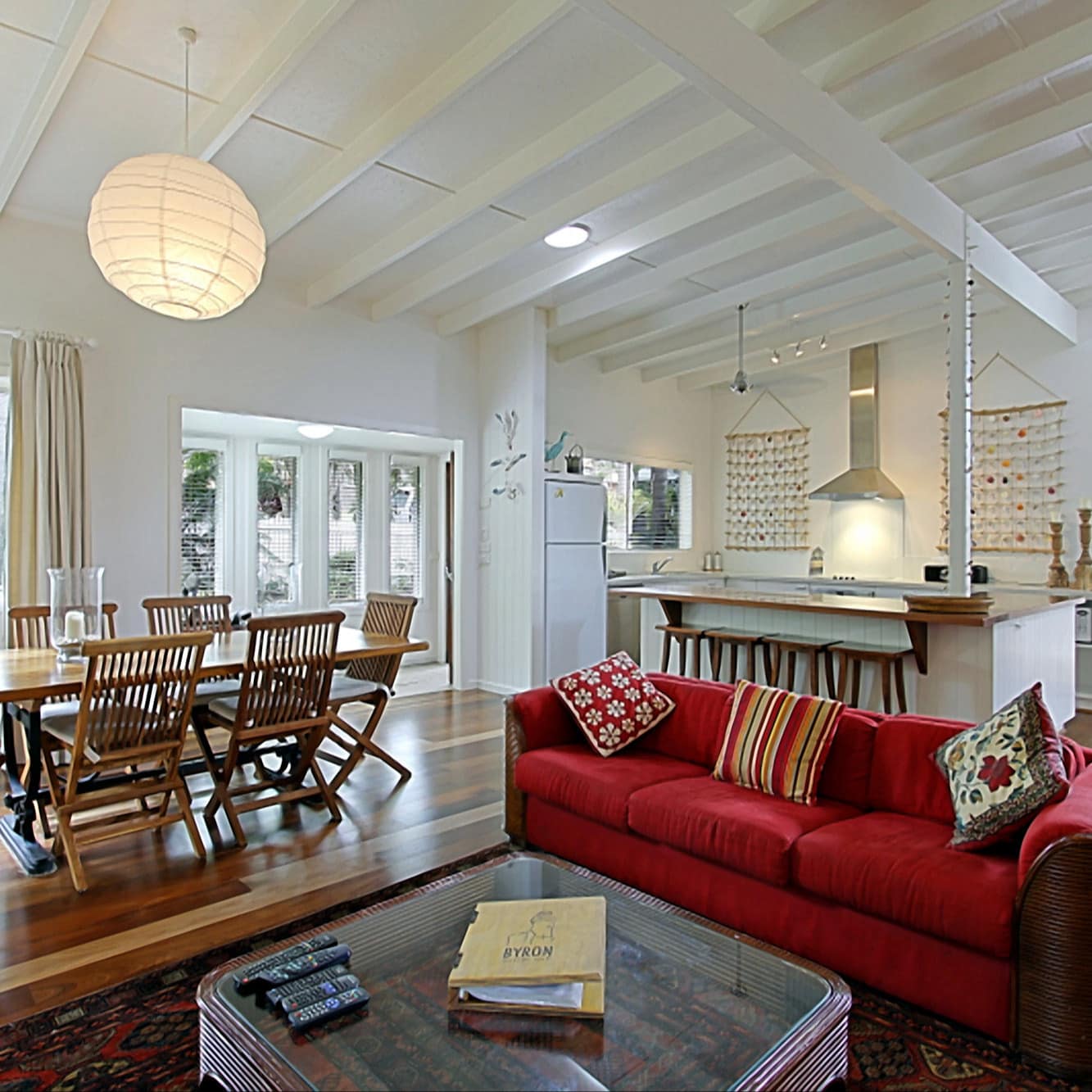 Living room, dining area, and open kitchen of the Allure beach house in Byron with hardwood floors and bright windows