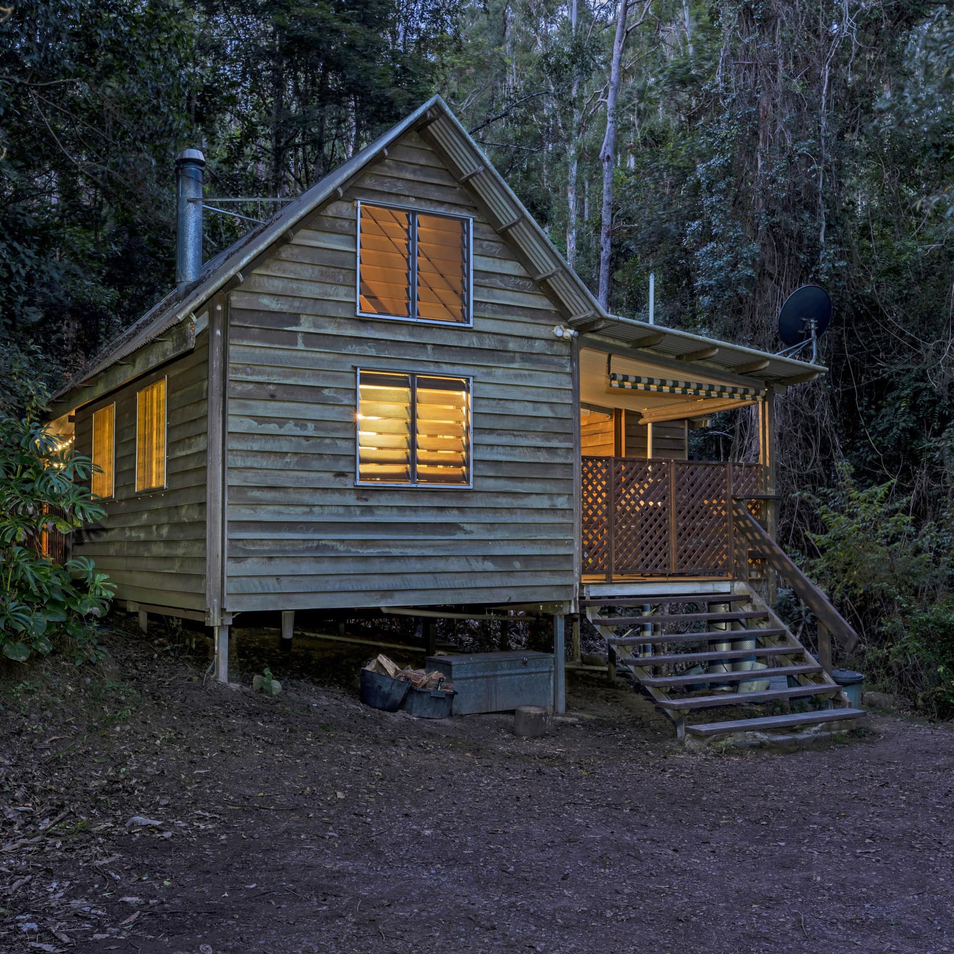 Nighttime view of a wood cabin surrounded by thick forest.