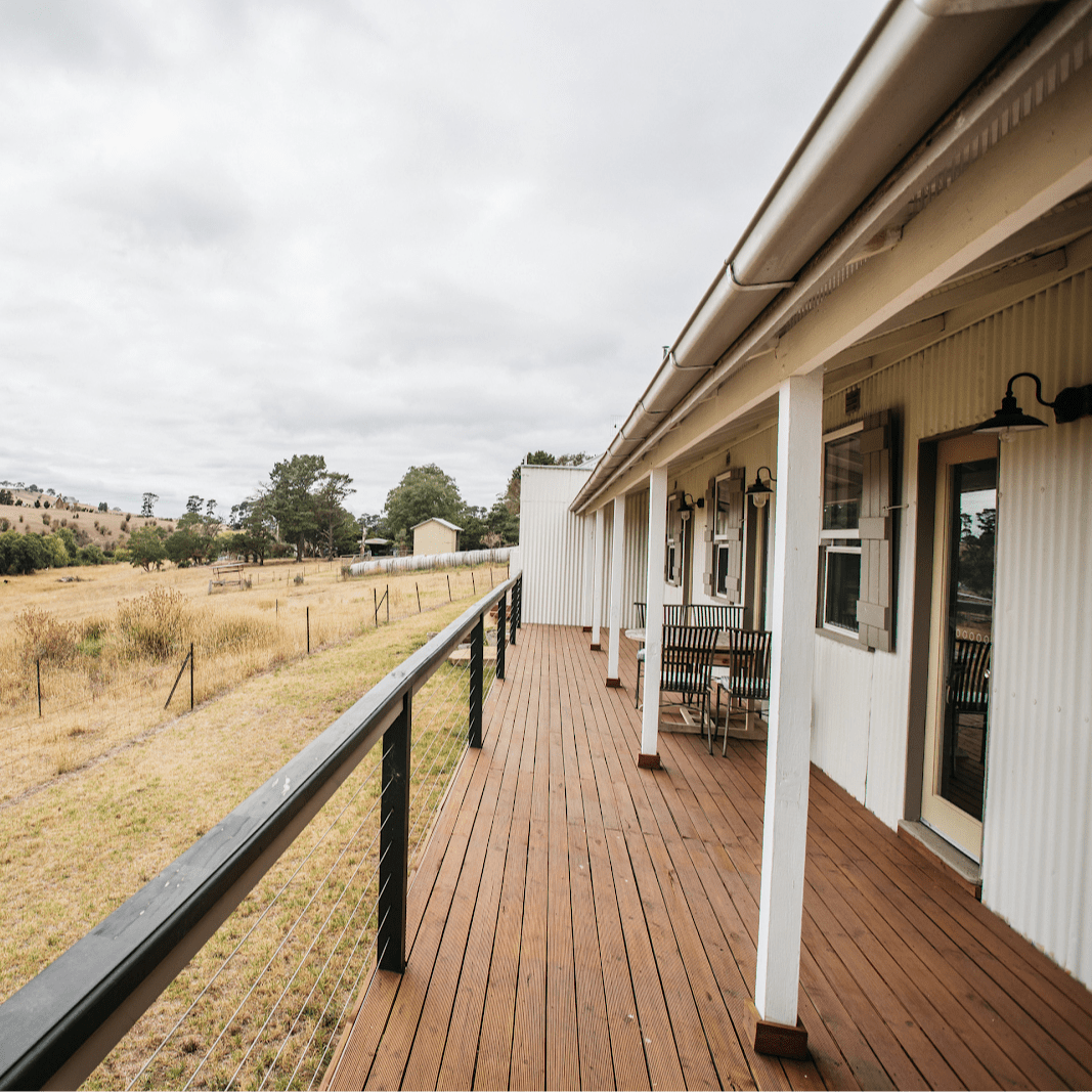 View from the patio of a rustic, ranch-style home overlooking rambling hills of the countryside.