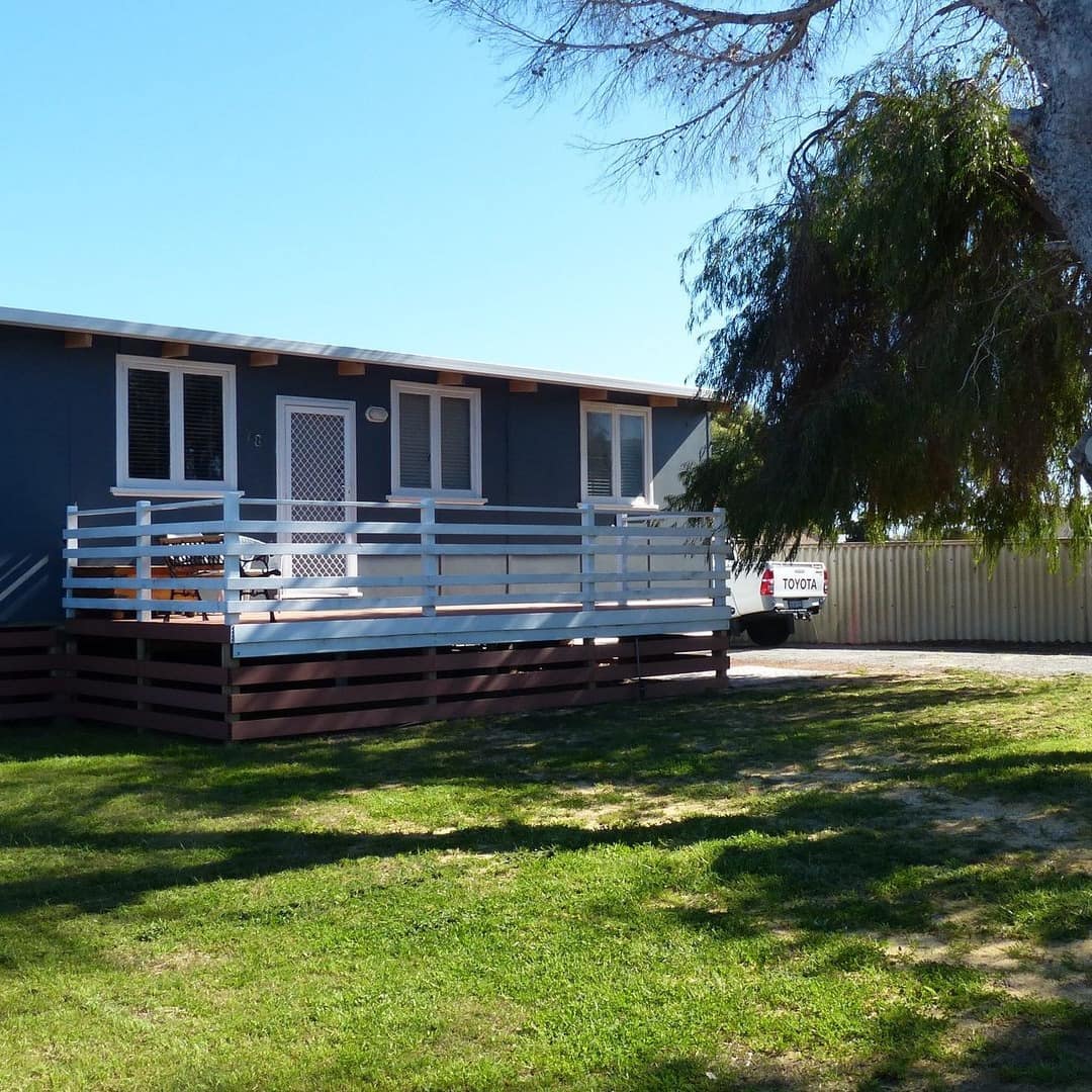 Blue cottage with front porch and landscaped front lawn.