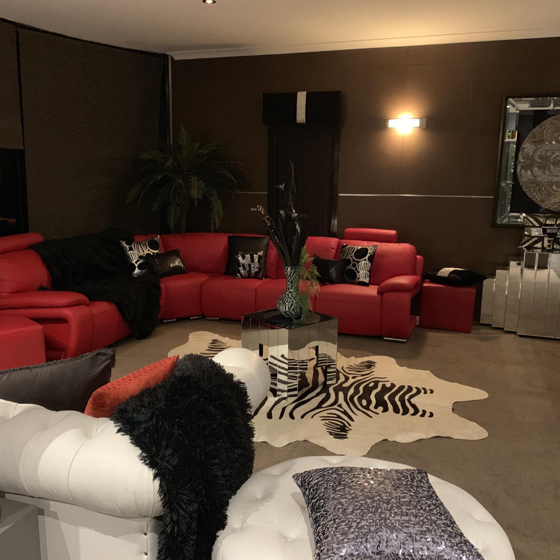 Living room with grey walls and carpet, red sectional, mirrored furniture, and zebra print rug.