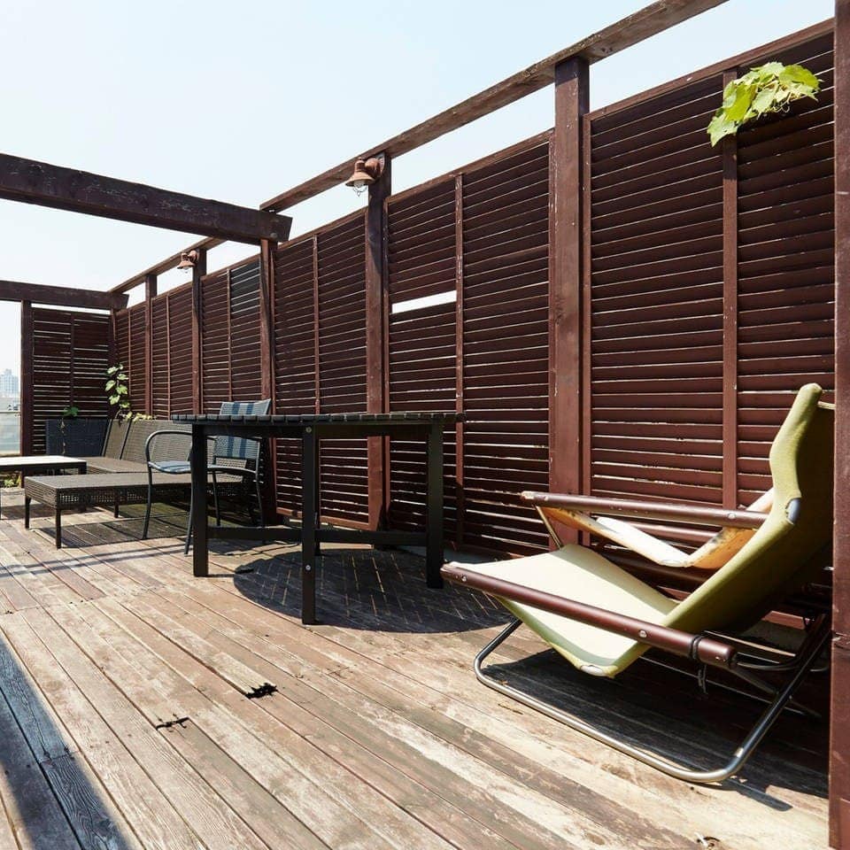 Weathered wood-plank patio with open roof, wood-slat privacy walls, and view of city skyline