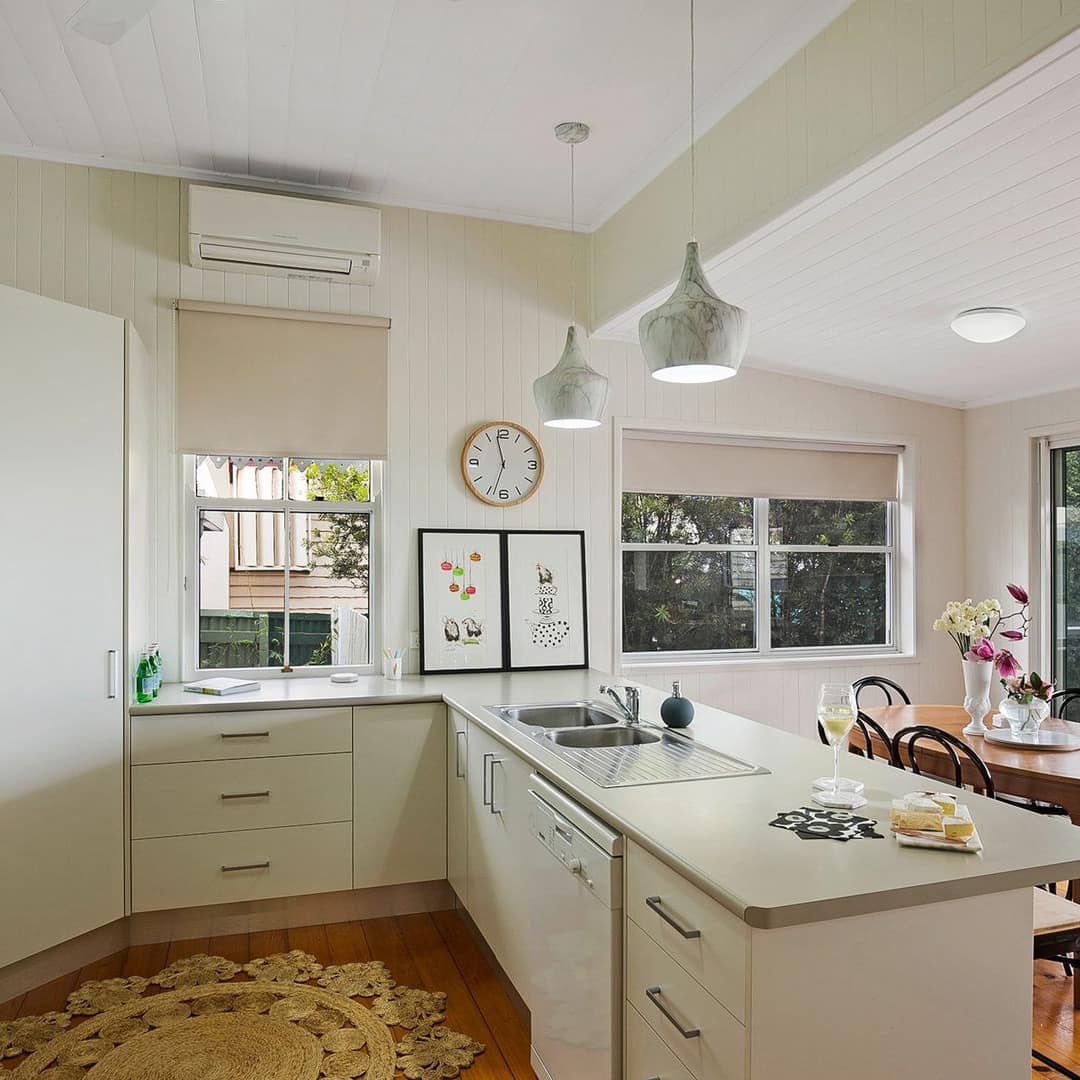 An elegant kitchen with dining area and attached screened porch, hardwood floors, white cabinets, and countertops.