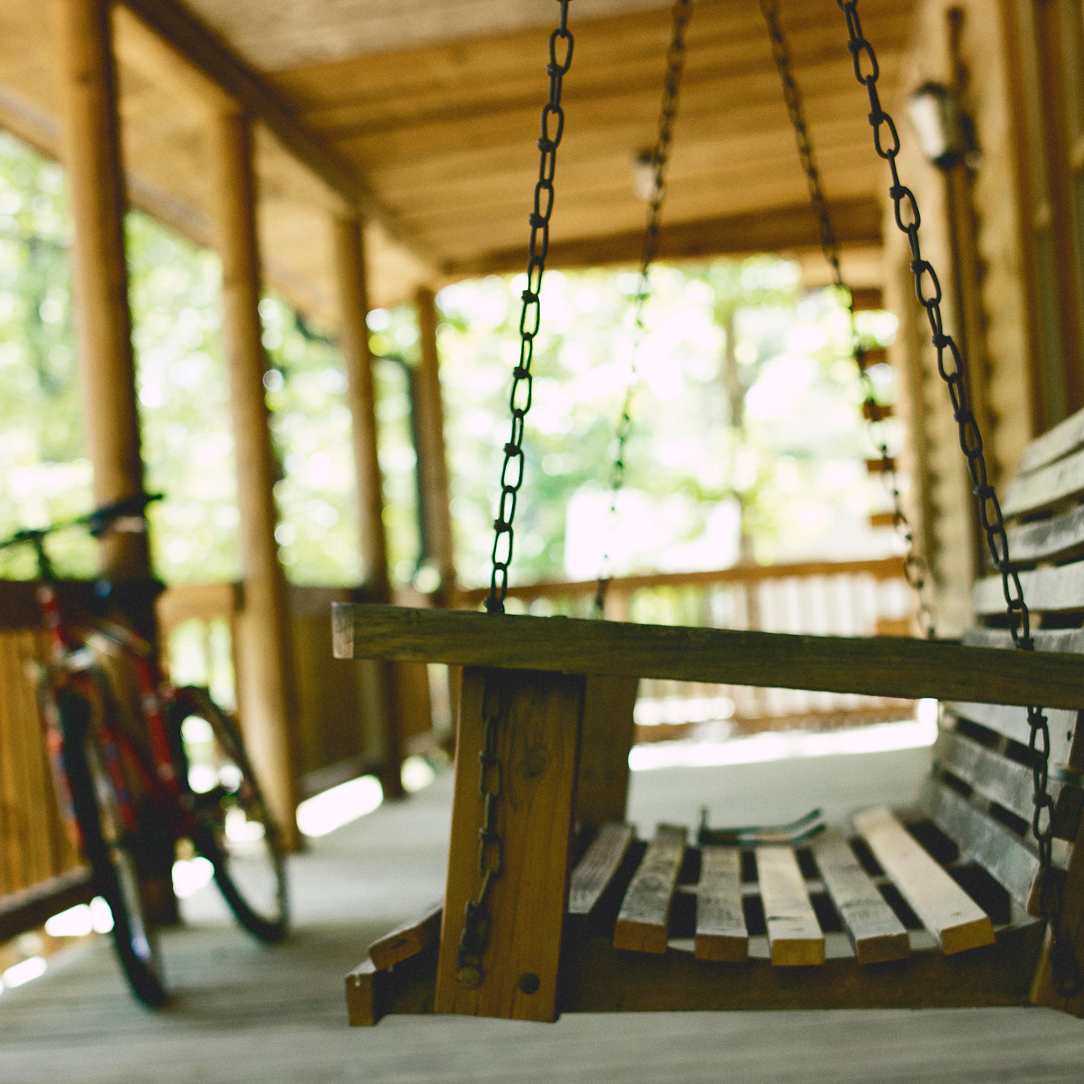 A swing on a log cabin porch and a child’s bike reflect the fun of a family cabin