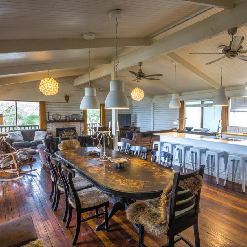 Open living room and kitchen with hardwood floors, an antique dining table and modern kitchen.