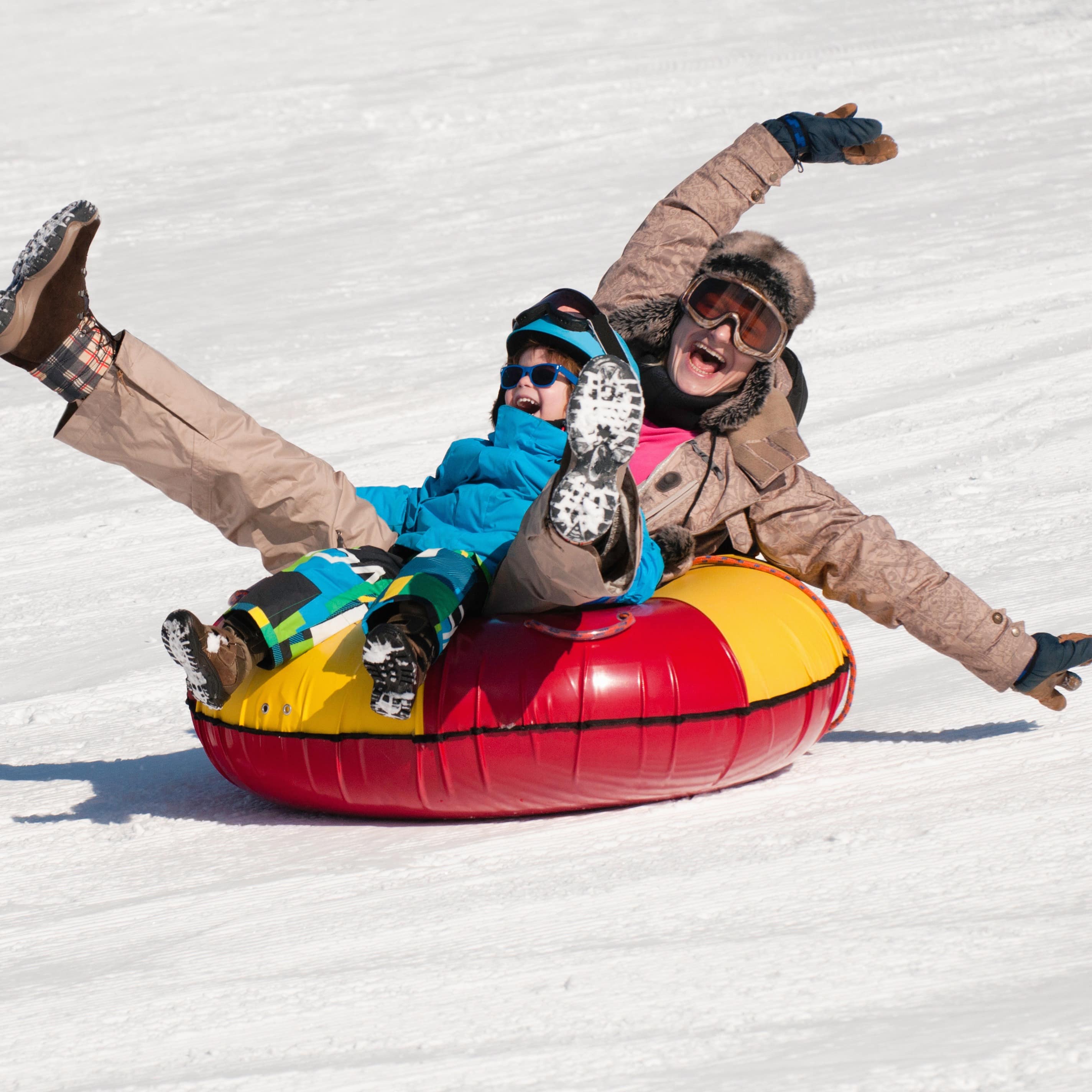 Woman and little boy snow tubing