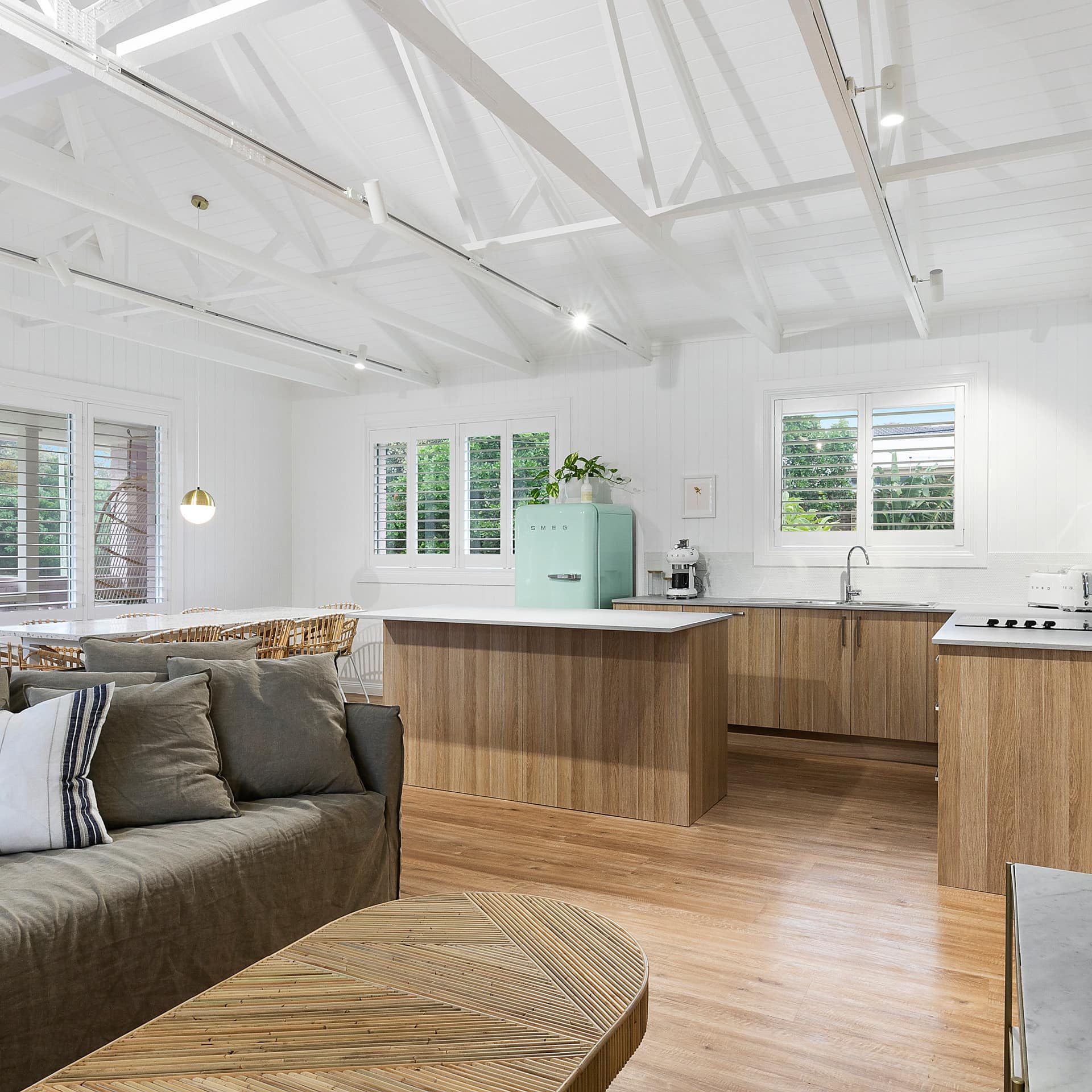 High white ceilings, timber floors and modern, retro styling living and kitchen area in a beach holiday home