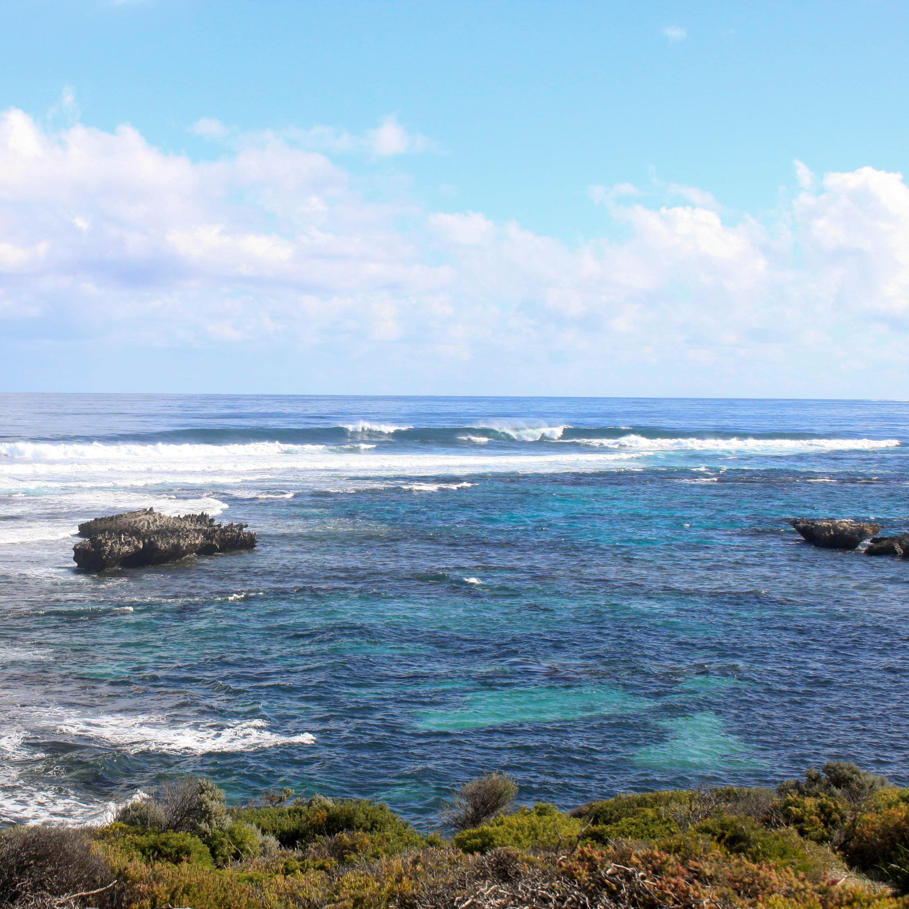 Coast of Perth with reefs that appear purple accented against aquamarine waters and crashing waves
