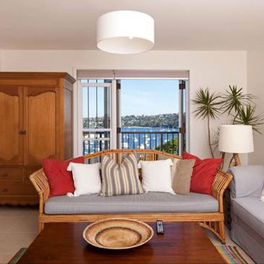 Living room with beige tile floors and walls, bamboo wood sofa, wood coffee table, attached balcony with ocean views.