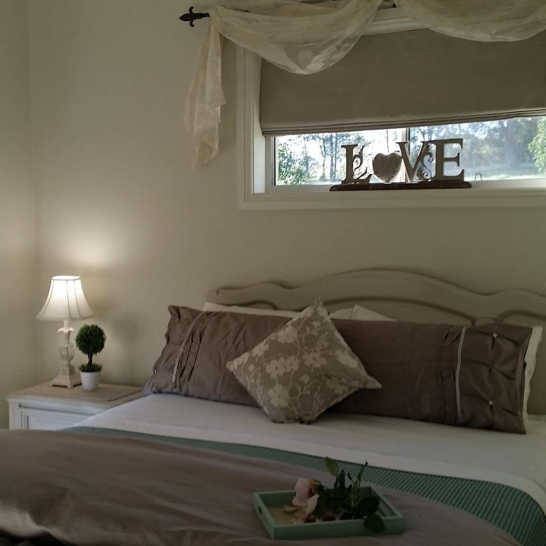 Cosy, light and airy bedroom with bed neatly made and decorated in neutral beige with a welcoming tray on the edge of the bed