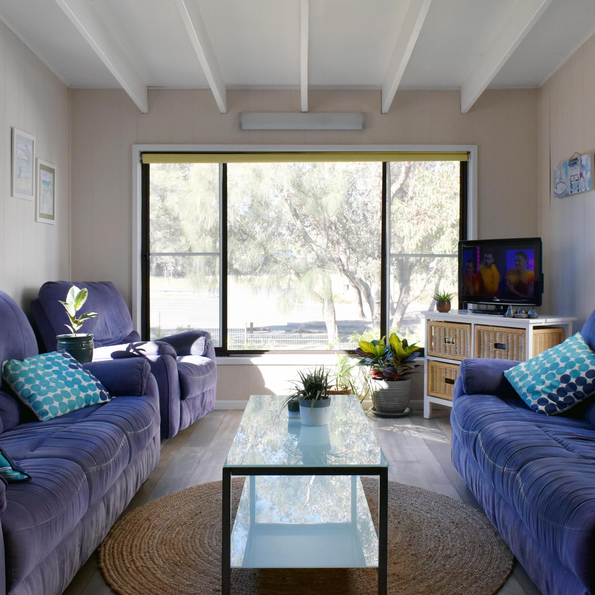 Large, comfy, blue couches in cosy lounge with large windows on each wall filling the room with bright sunshine