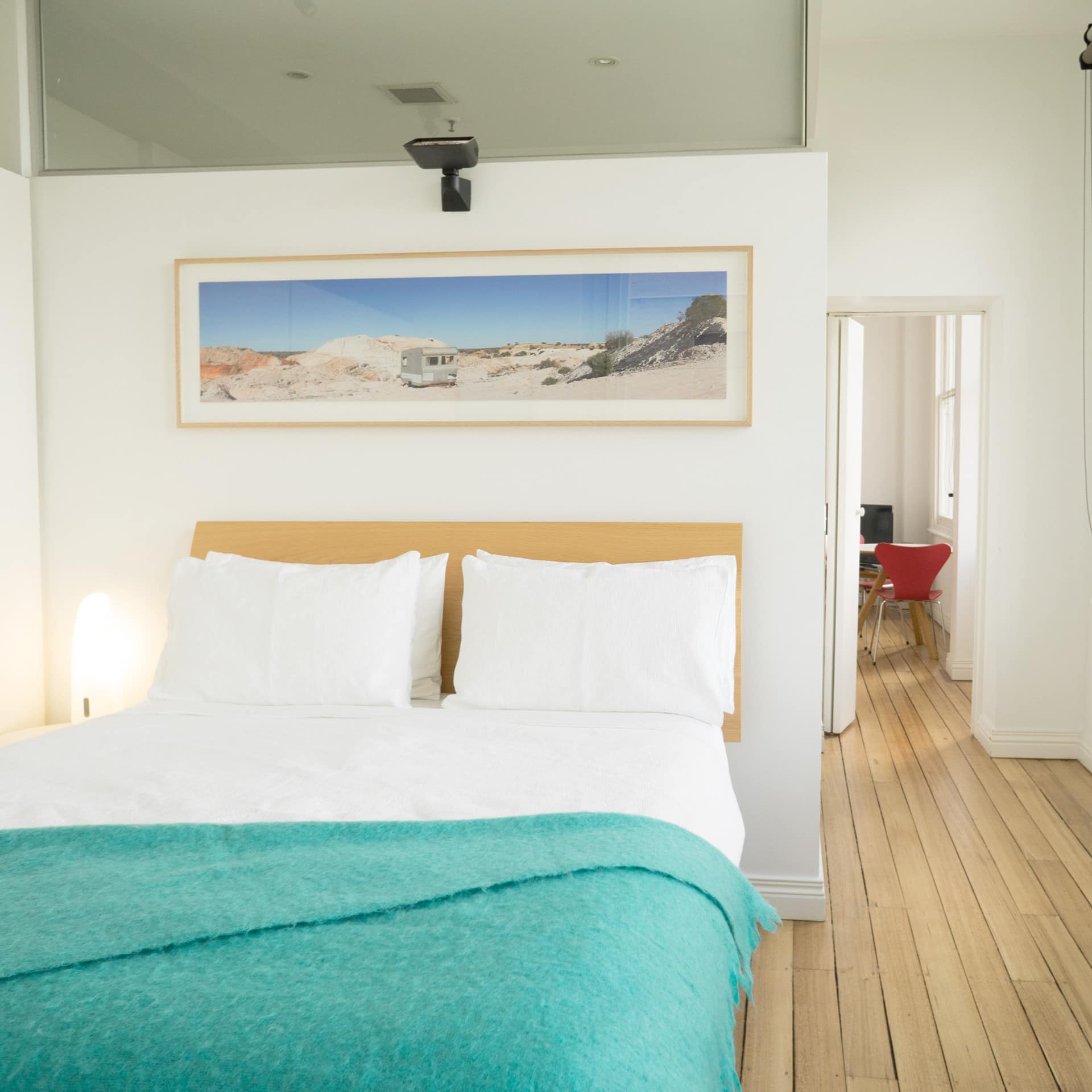 Bright bedroom with hardwood floors, white walls, and a king size bed, blue and white bedding.