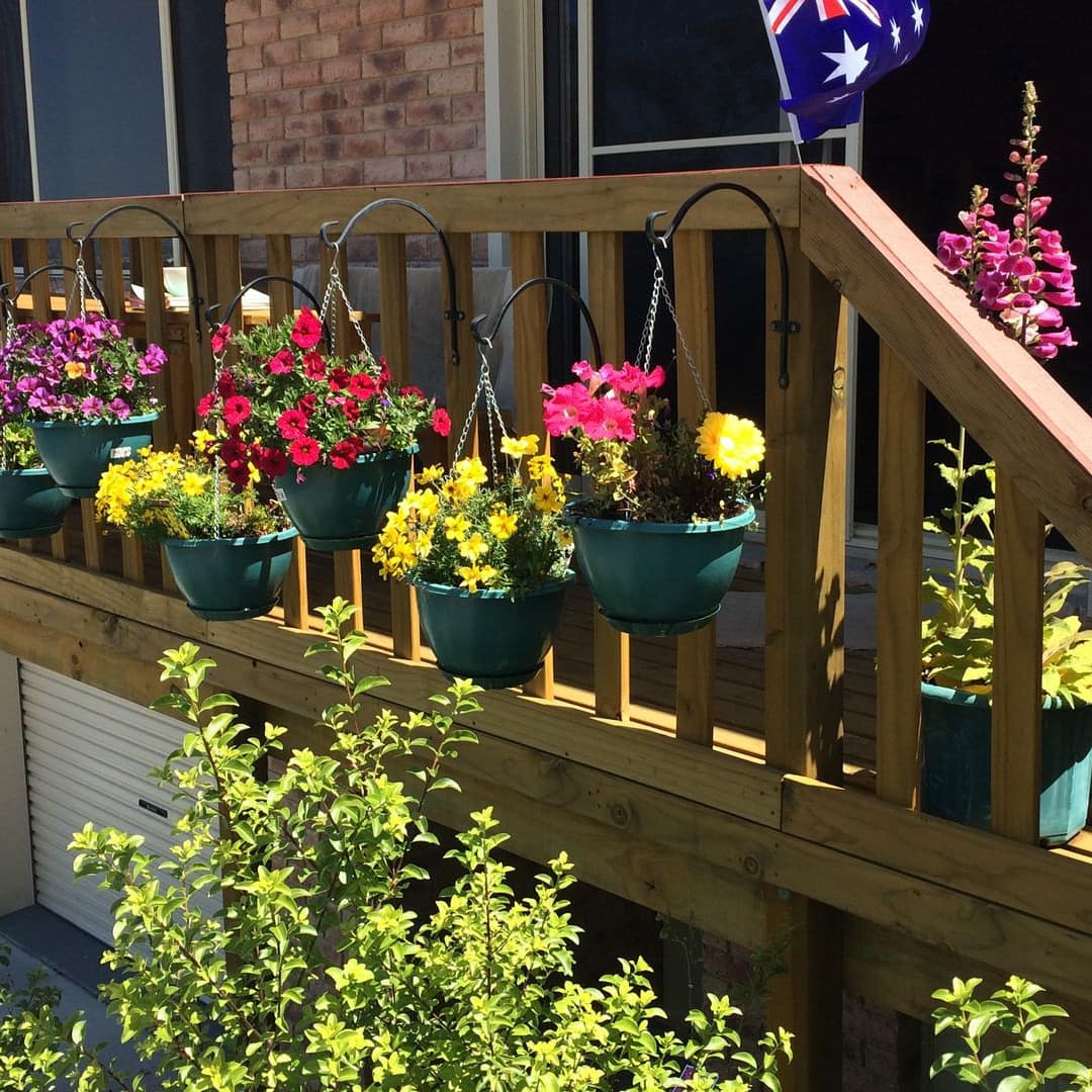 Wood balcony of Claremont apartment with baskets of hanging flowers and mountain views