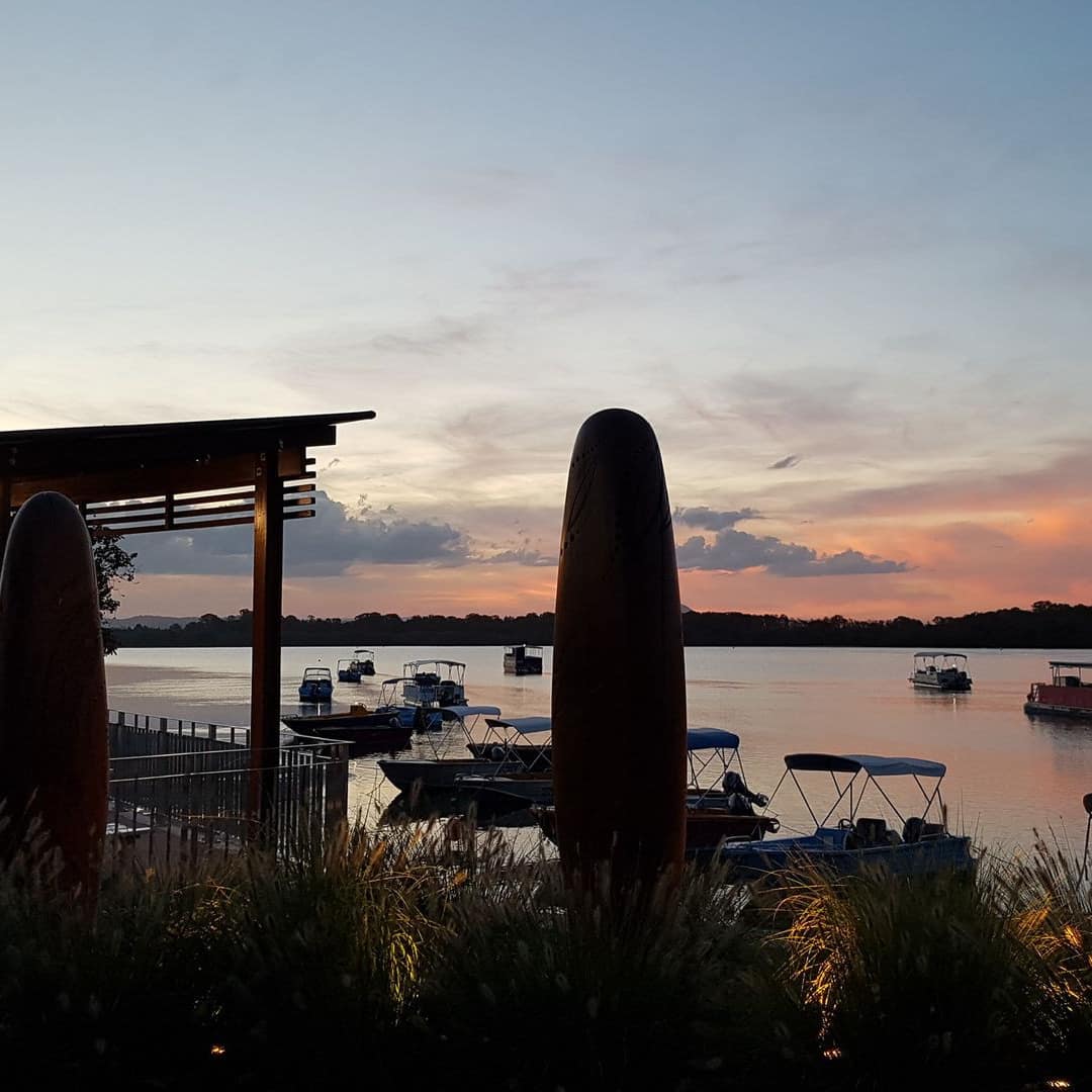 A covered deck with a view of Maroochy River at sunset with boats for hire in the water.