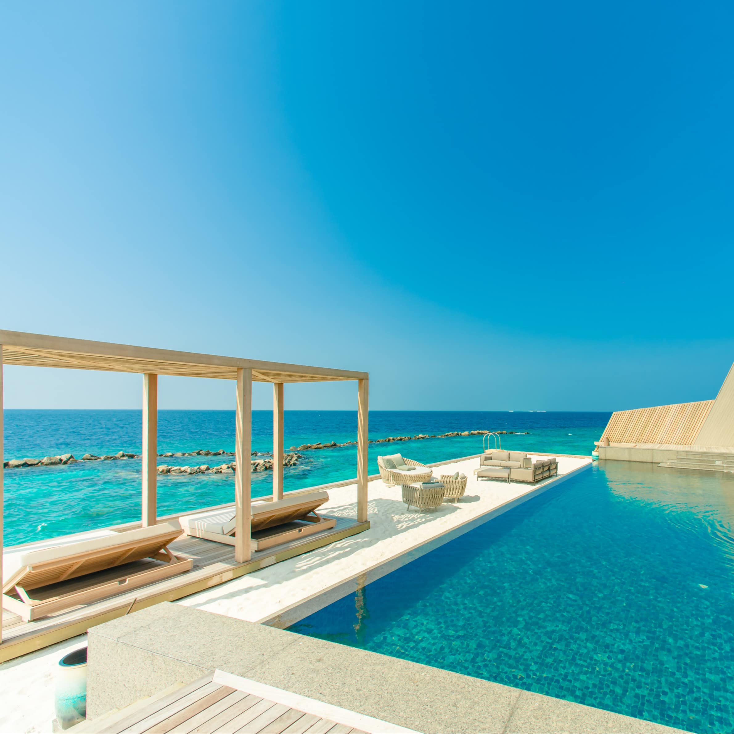Beachfront house with private pool, floating veranda with a sofa, chairs, and futons under an arbor and the crystal ocean