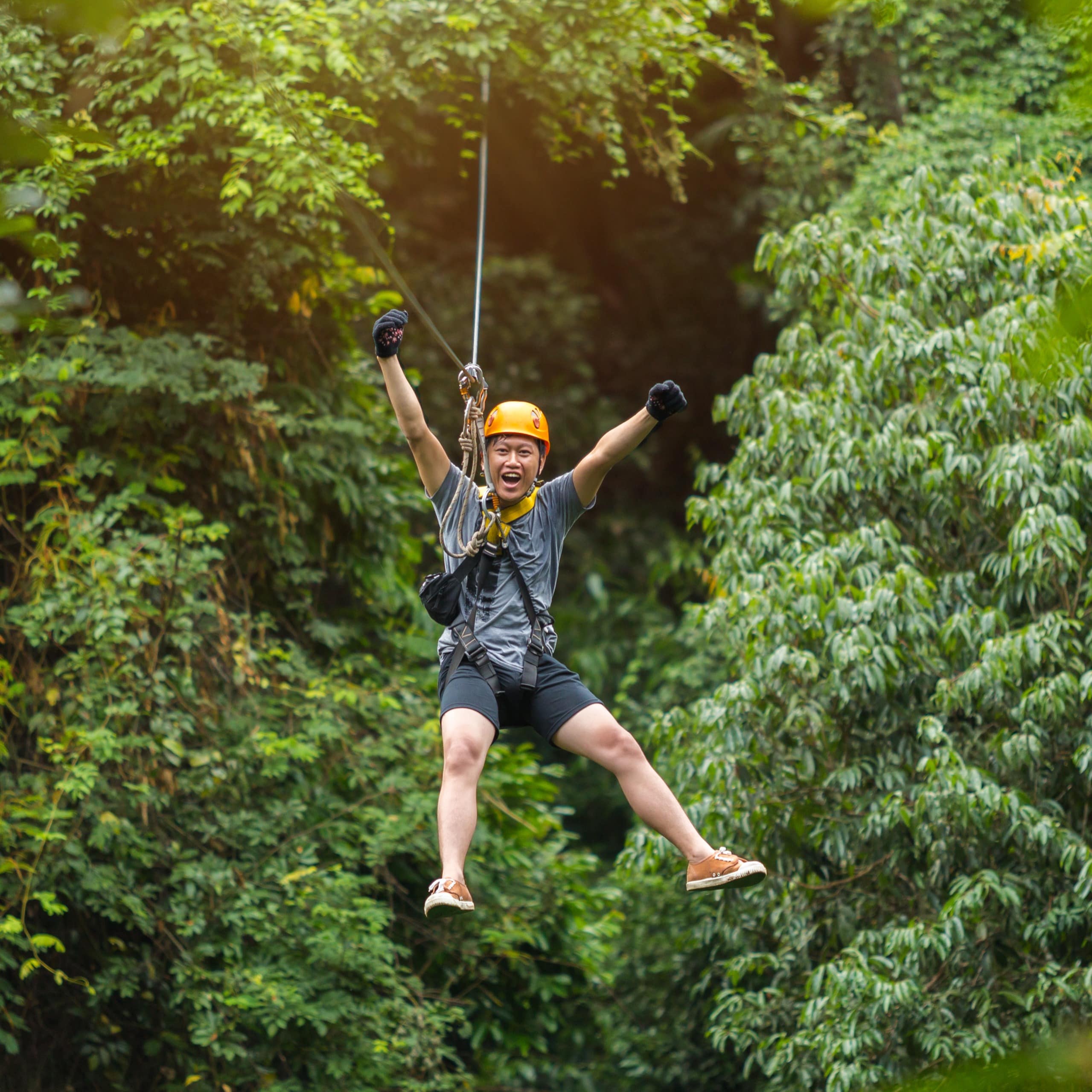 Man zip lining through forest