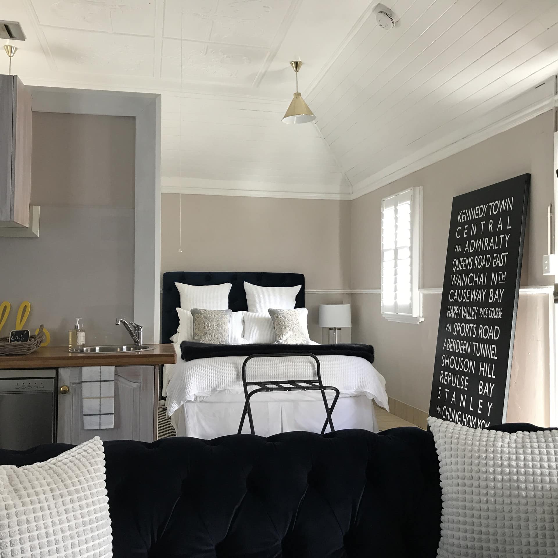 Baker’s Cottage open studio space with black cloth sofa, kitchen and queen-sized bed with black, white and warm gray decor.