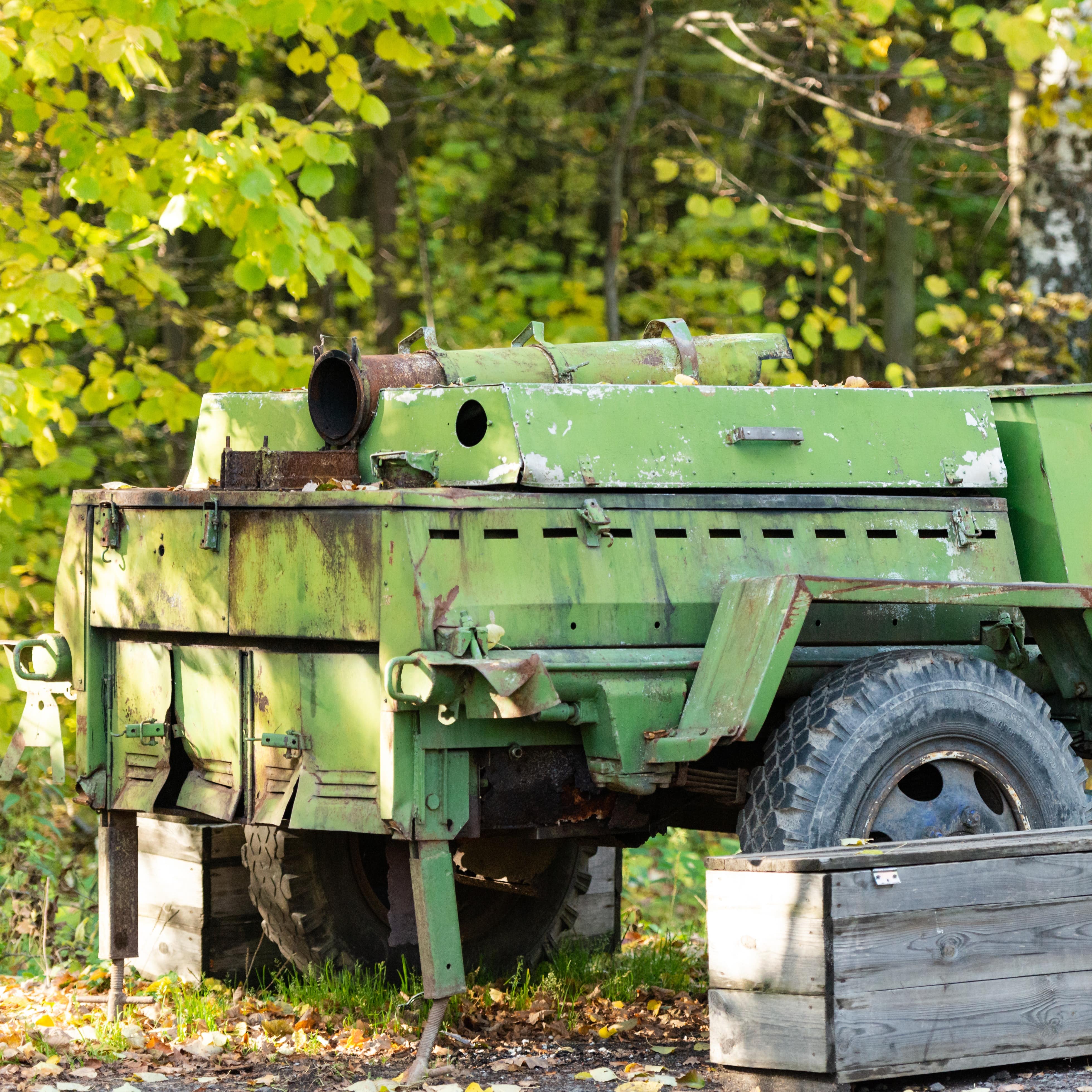 Old green military trailer with kitchen on display by trees