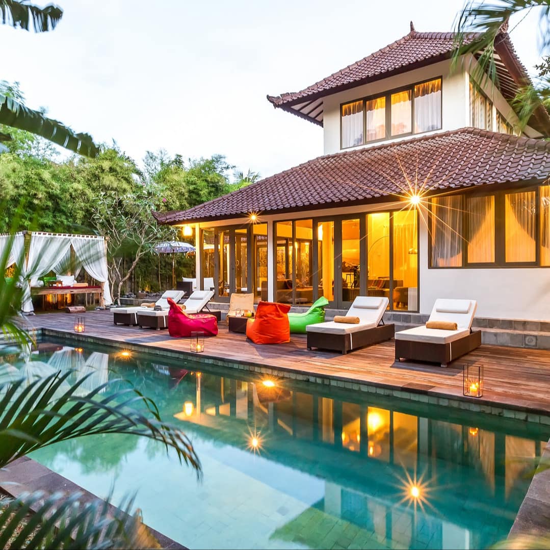 Traditional Bali 2-storey villa with tile roof, floor-to-ceiling windows, and a private pool with lounge area