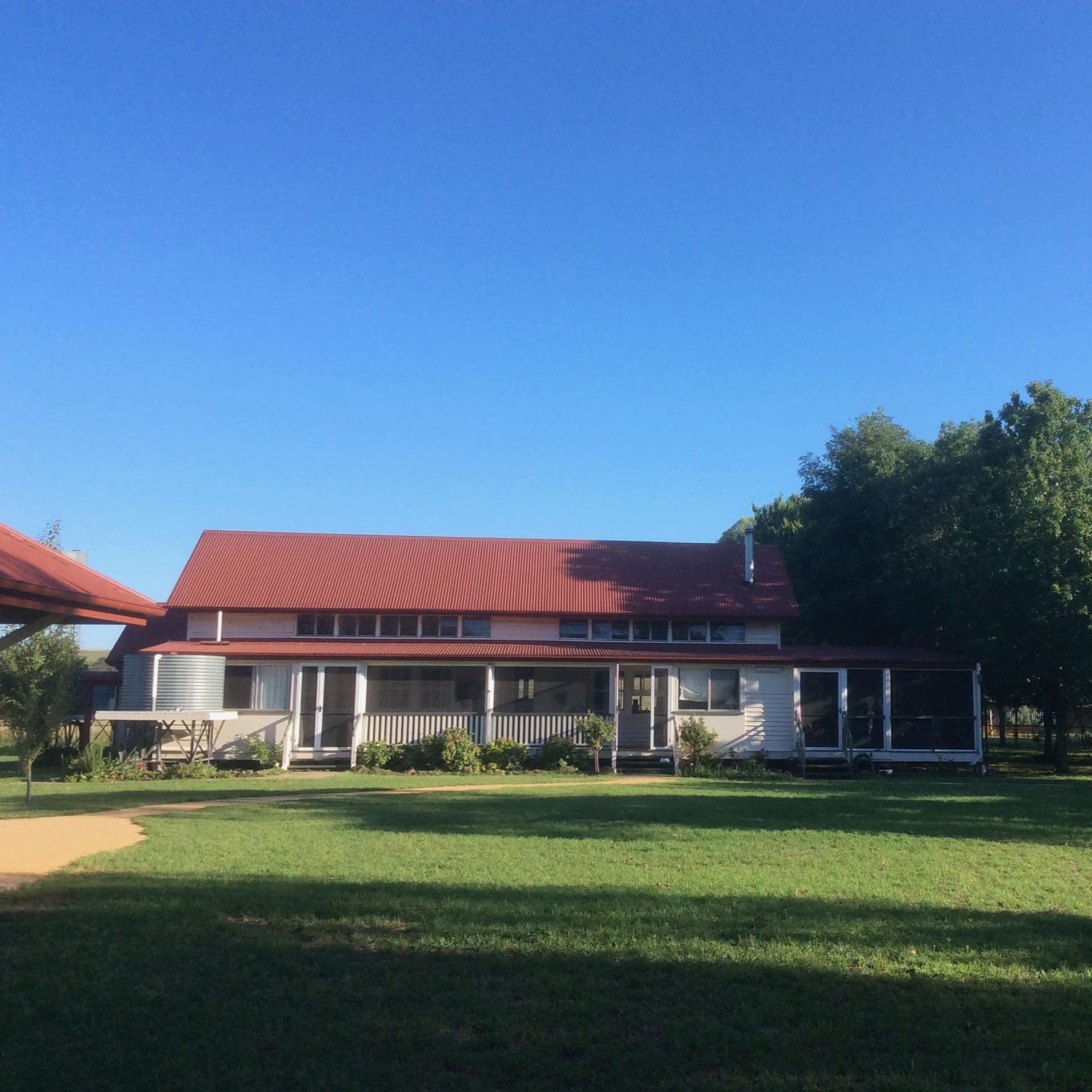 Exterior view of restored country school house with white siding, red roof, and spacious lawn.