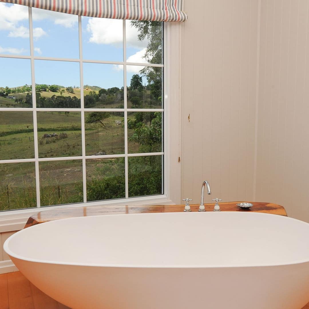A spa tub next to a window overlooking a green field