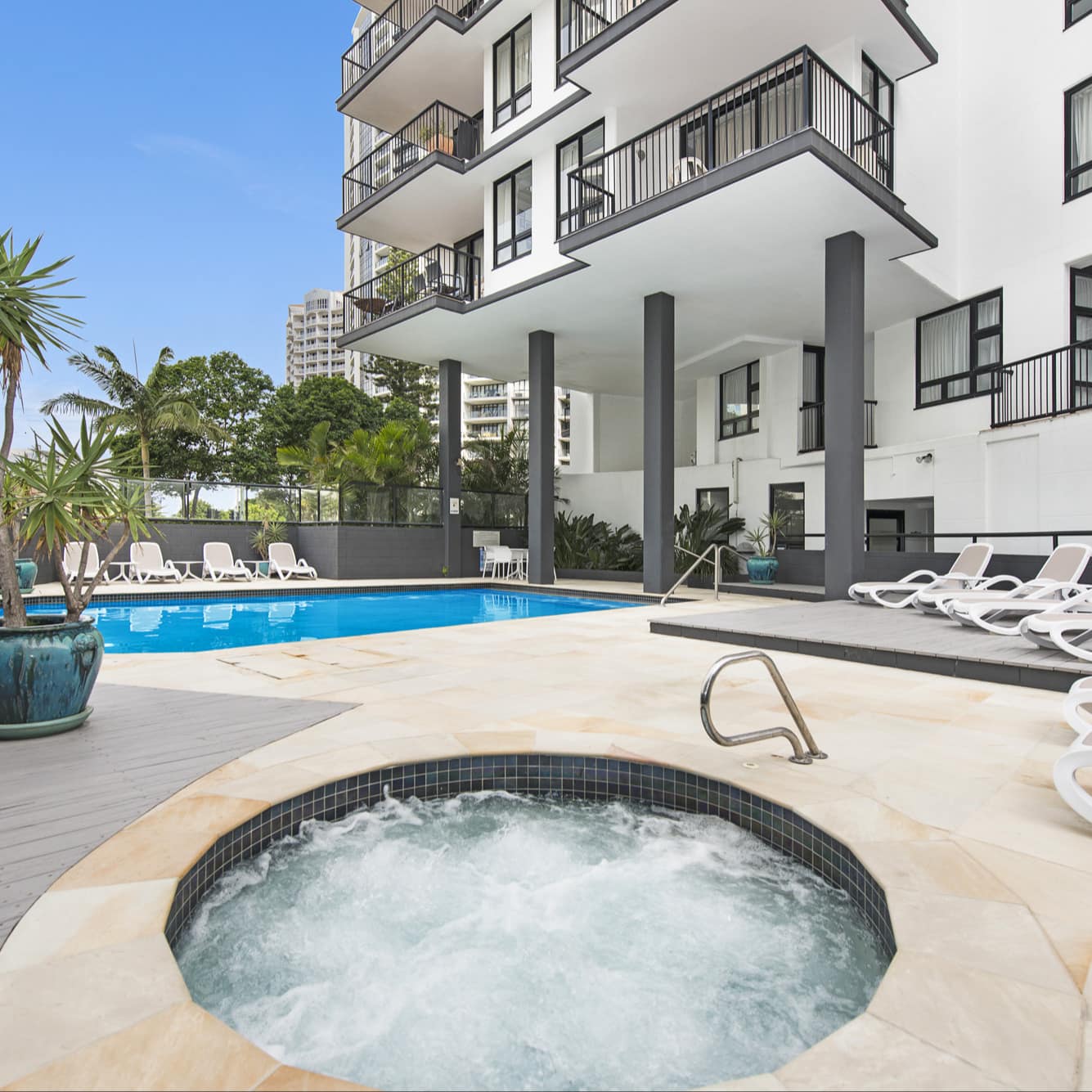 Modern apartment building with outdoor pool and hot tub where you can relax on a lounge chair