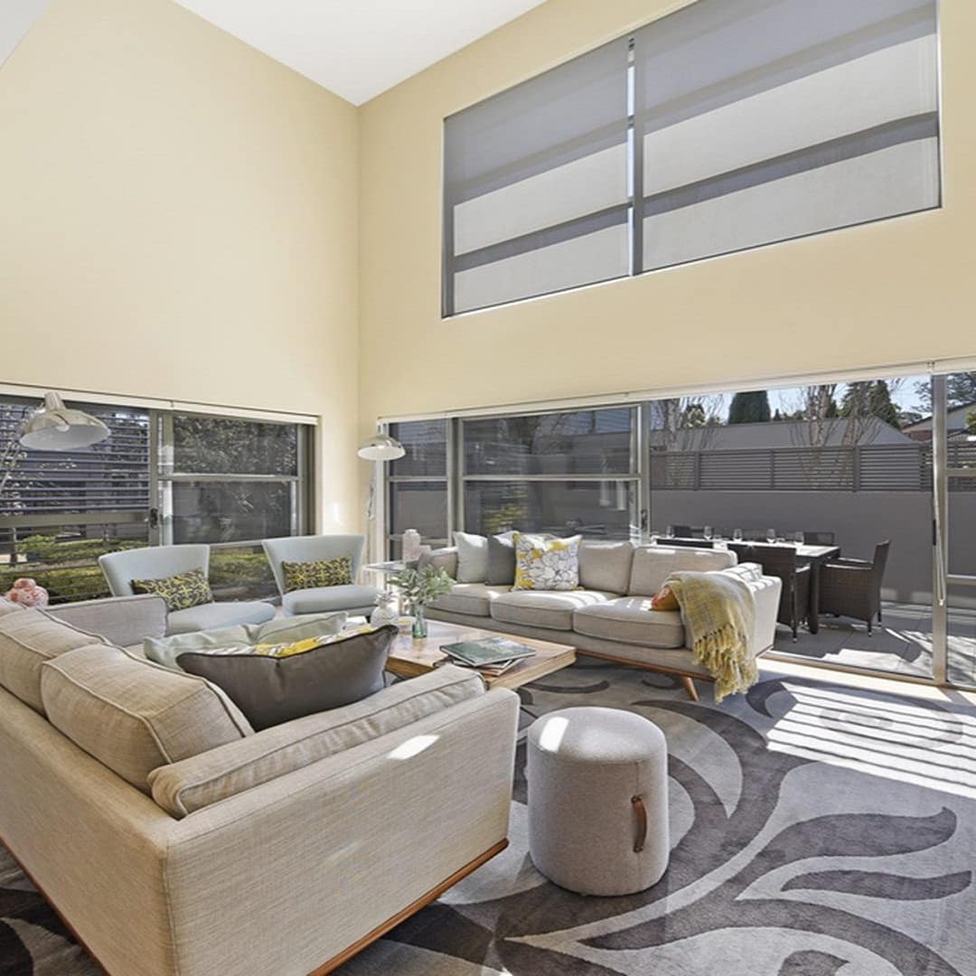 Sunny living room with canvas sofas and chairs, hardwood floors, and large sliding glass doors that open onto a patio.