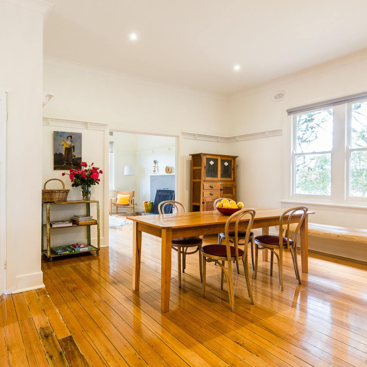 Open dining room with hardwood floors, white walls, wooden dining set, and vintage decor.