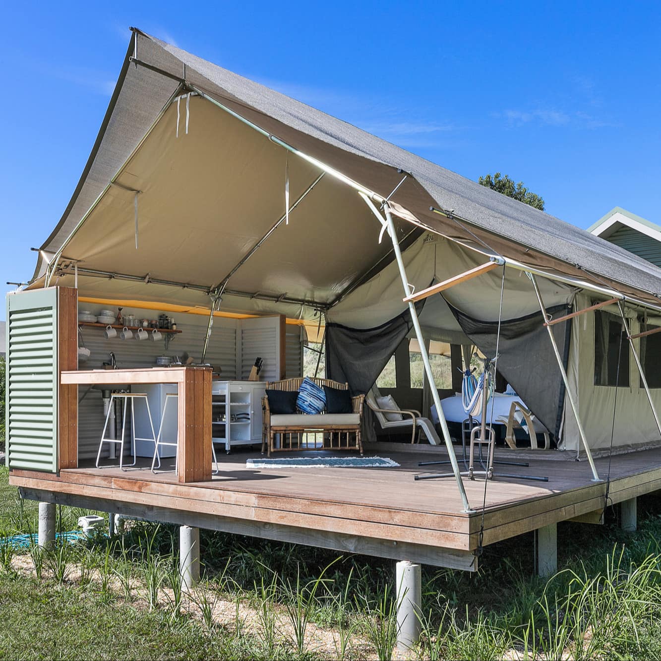 Farm glamping in a luxury tent with a king-sized bed and covered open-air living and dining area and a breakfast bar