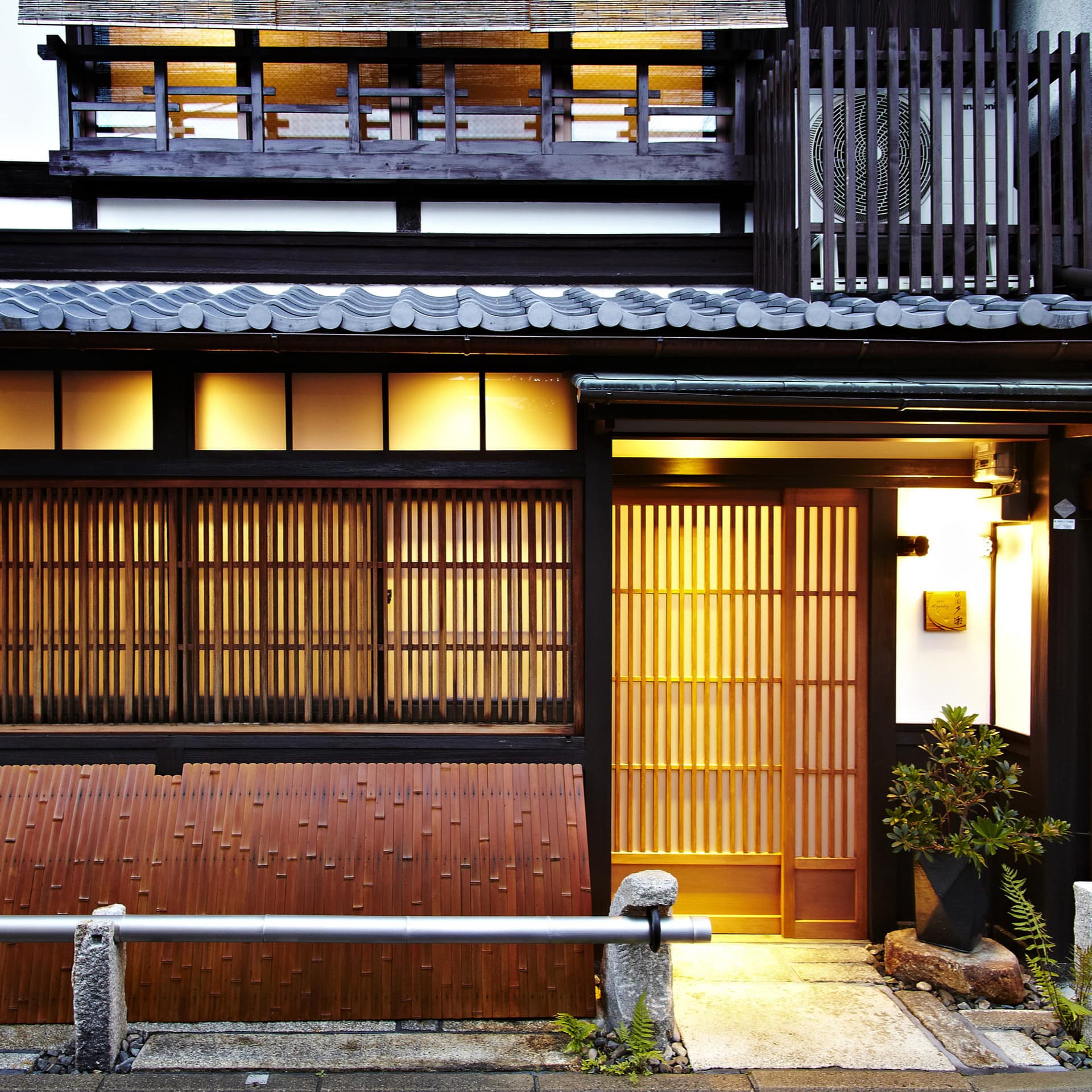 Exterior of traditional Japanese home with tiled roof and wooden slat windows.