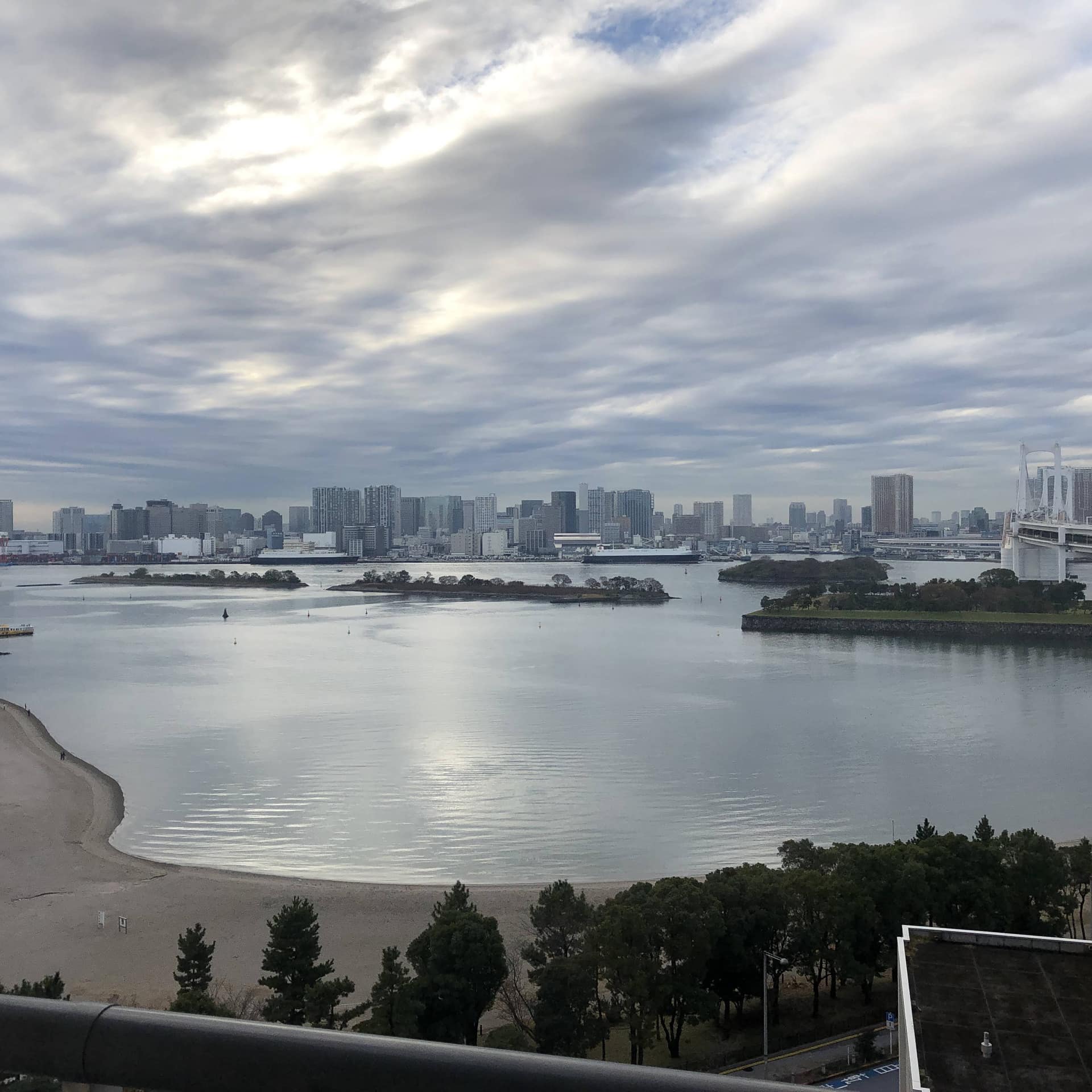 Serene view of the city skyline behind a calm body of water and expansive sky