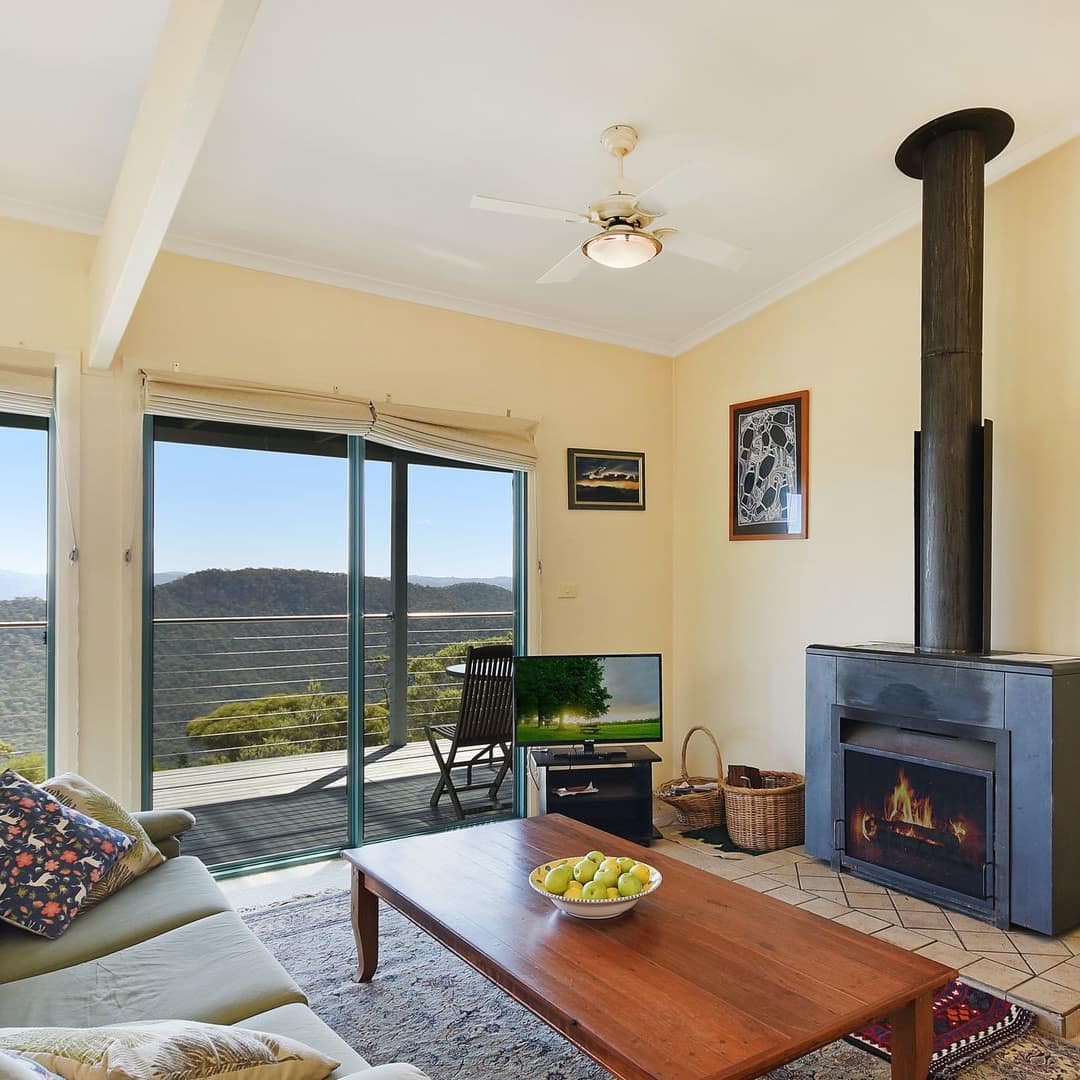 Sunken living room, two plush sofas, wood coffee table, gas fireplace, and attached veranda overlooking the valley.