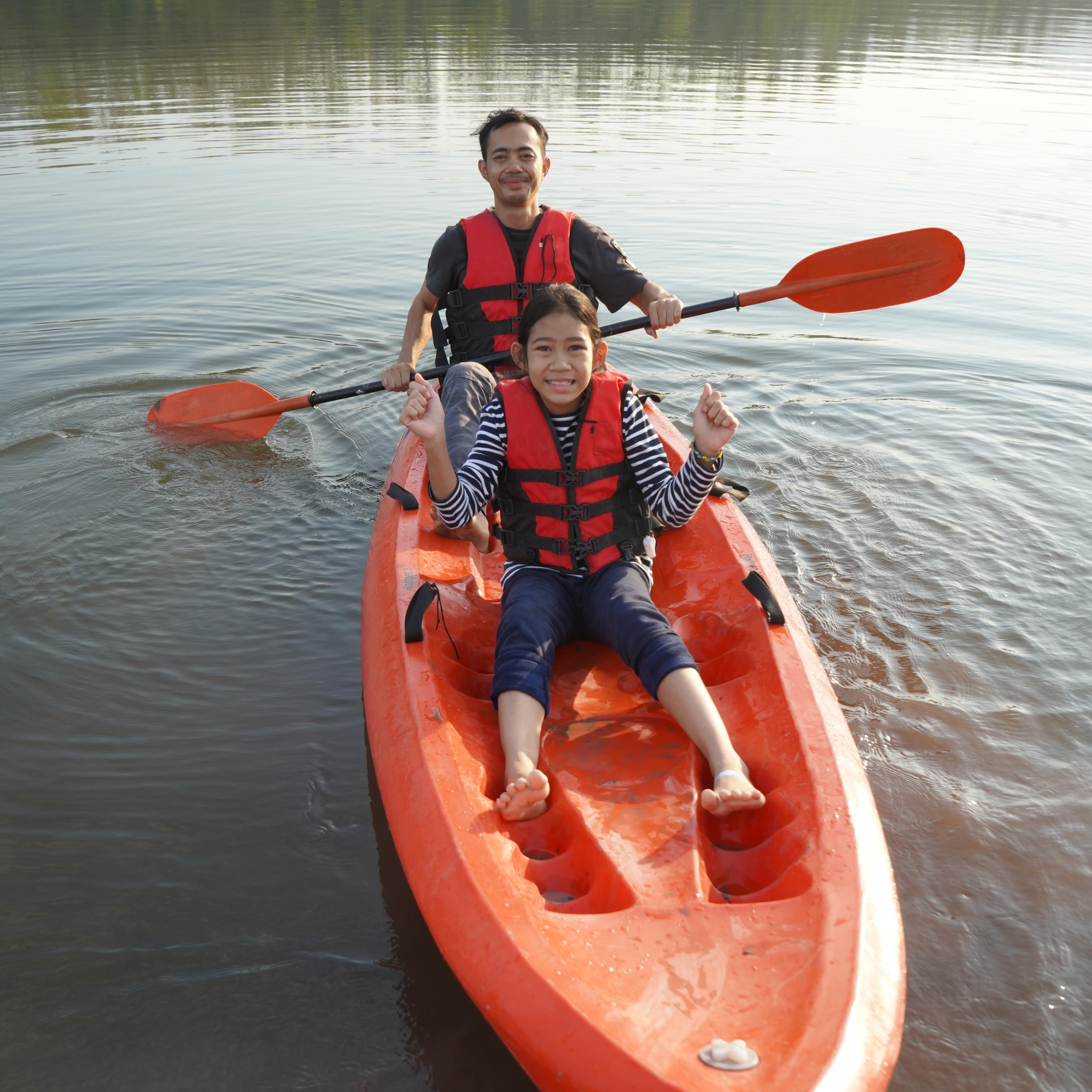 Father and daughter rowing in a kayak on calm waters